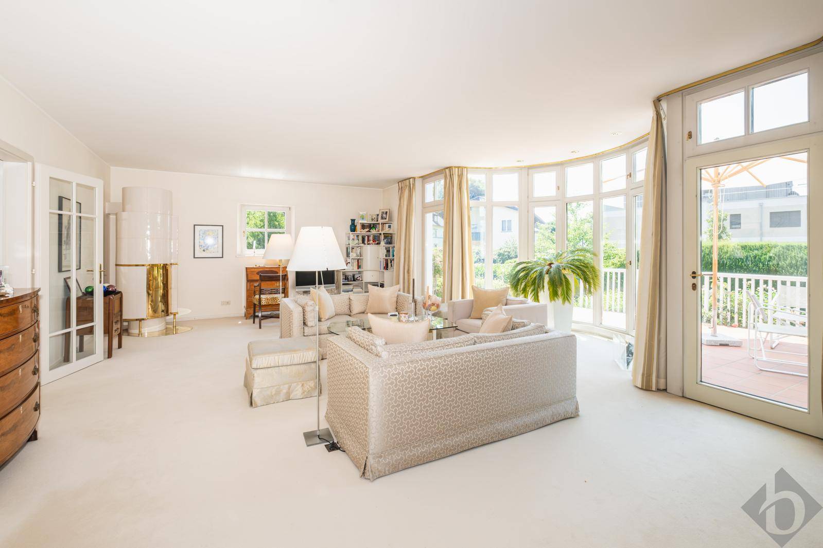 Geräumiges Wohnzimmer mit großen Fenstern, gemütlichem Kachelofen und direktem Zugang zur Terrasse.