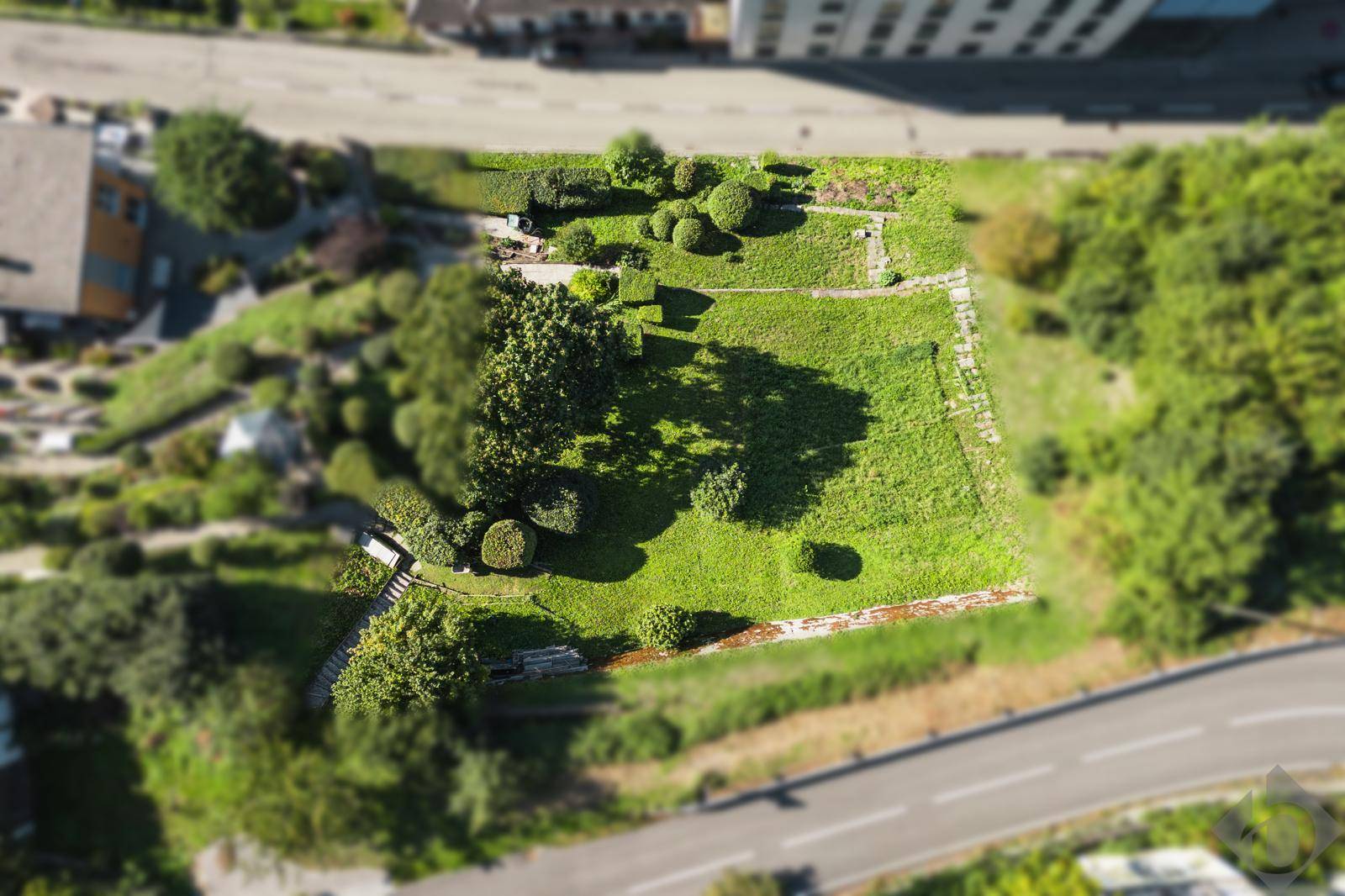 Luftaufnahme eines weitläufigen Gartengrundstücks mit terrassierten Ebenen und üppiger Vegetation.