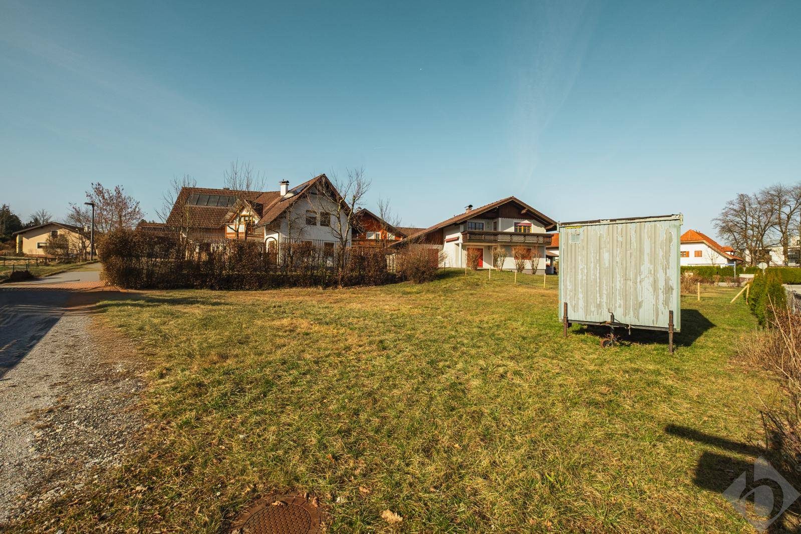 Weitläufiges Grundstück mit Grasfläche, einem Schuppen und traditionellen Häusern im Hintergrund.