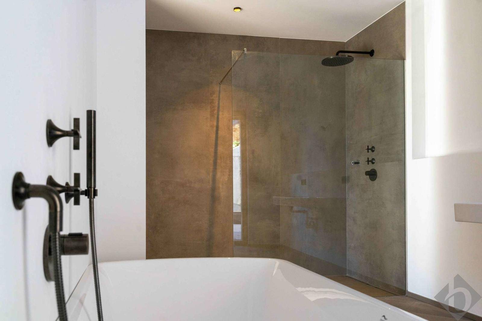 Modernes Badezimmer mit Badewanne, Regendusche und eleganten dunklen Armaturen.