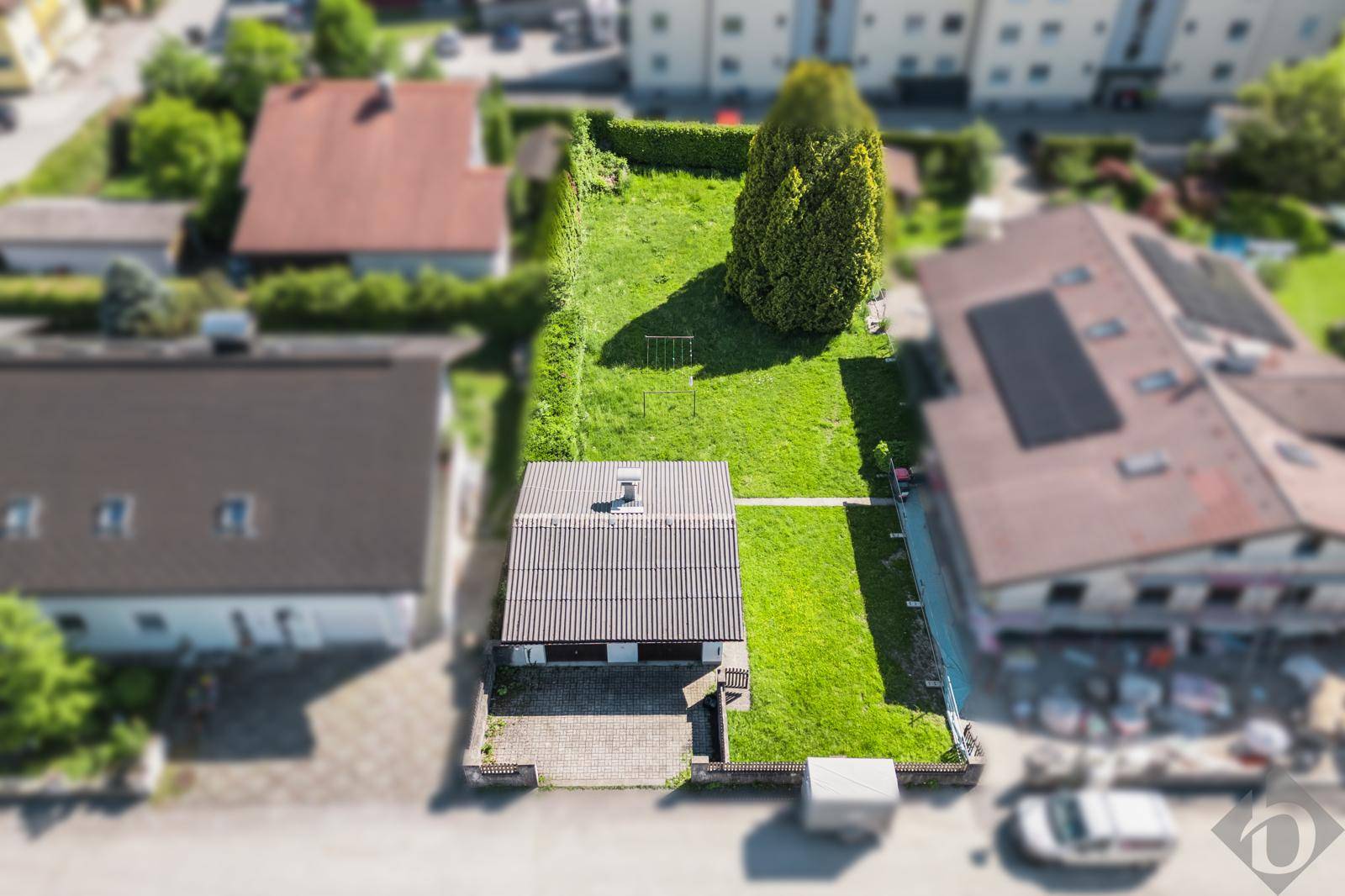 Luftaufnahme des Hauses mit gepflastertem Vorplatz und großem Gartenbereich dahinter.