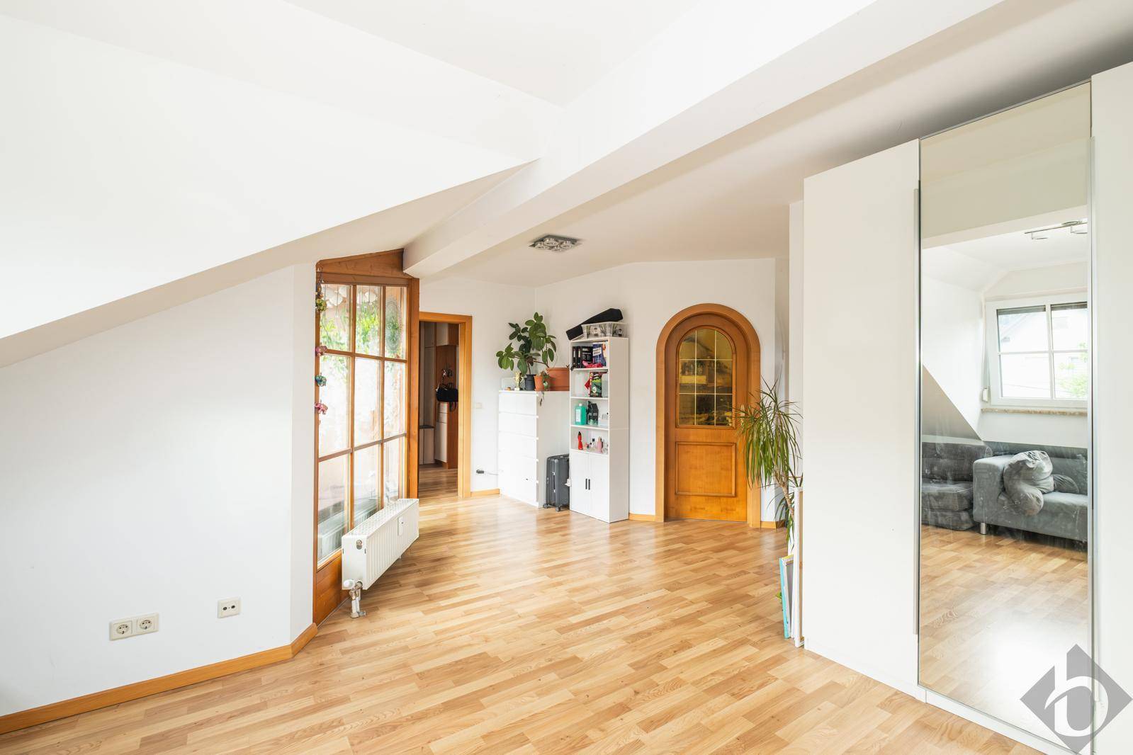 Heller Flur im Dachgeschoss mit Holzfußboden, Spiegelschrank und charmanten Holztüren.
