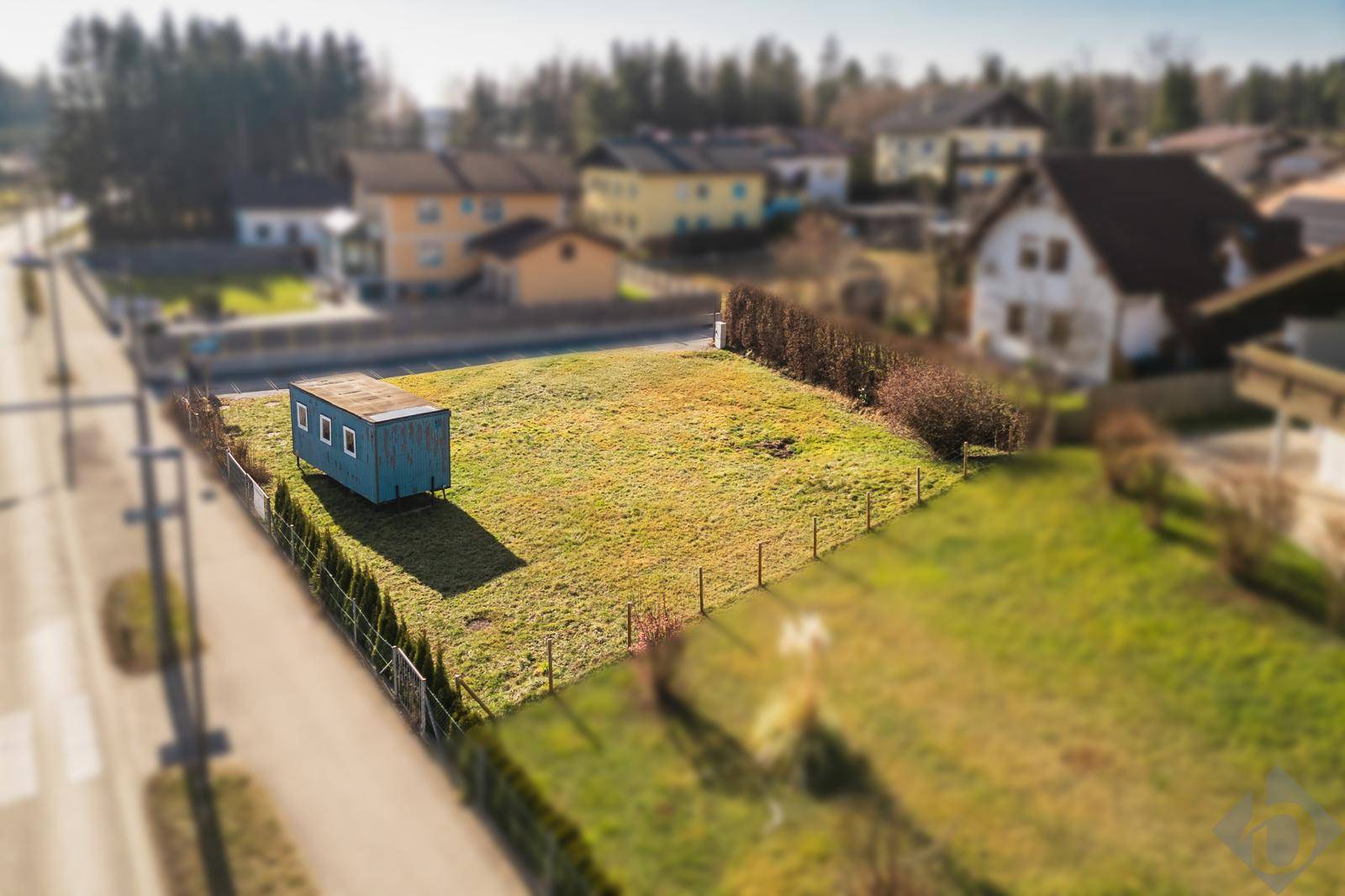 Luftaufnahme des Grundstücks mit einem blauen Schuppen, umgeben von Wohnhäusern und einer Straße.
