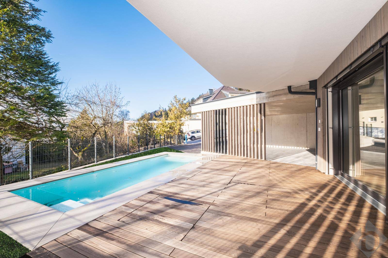 Sonnige Holzterrasse mit integriertem Pool und Blick auf die umliegende Natur.