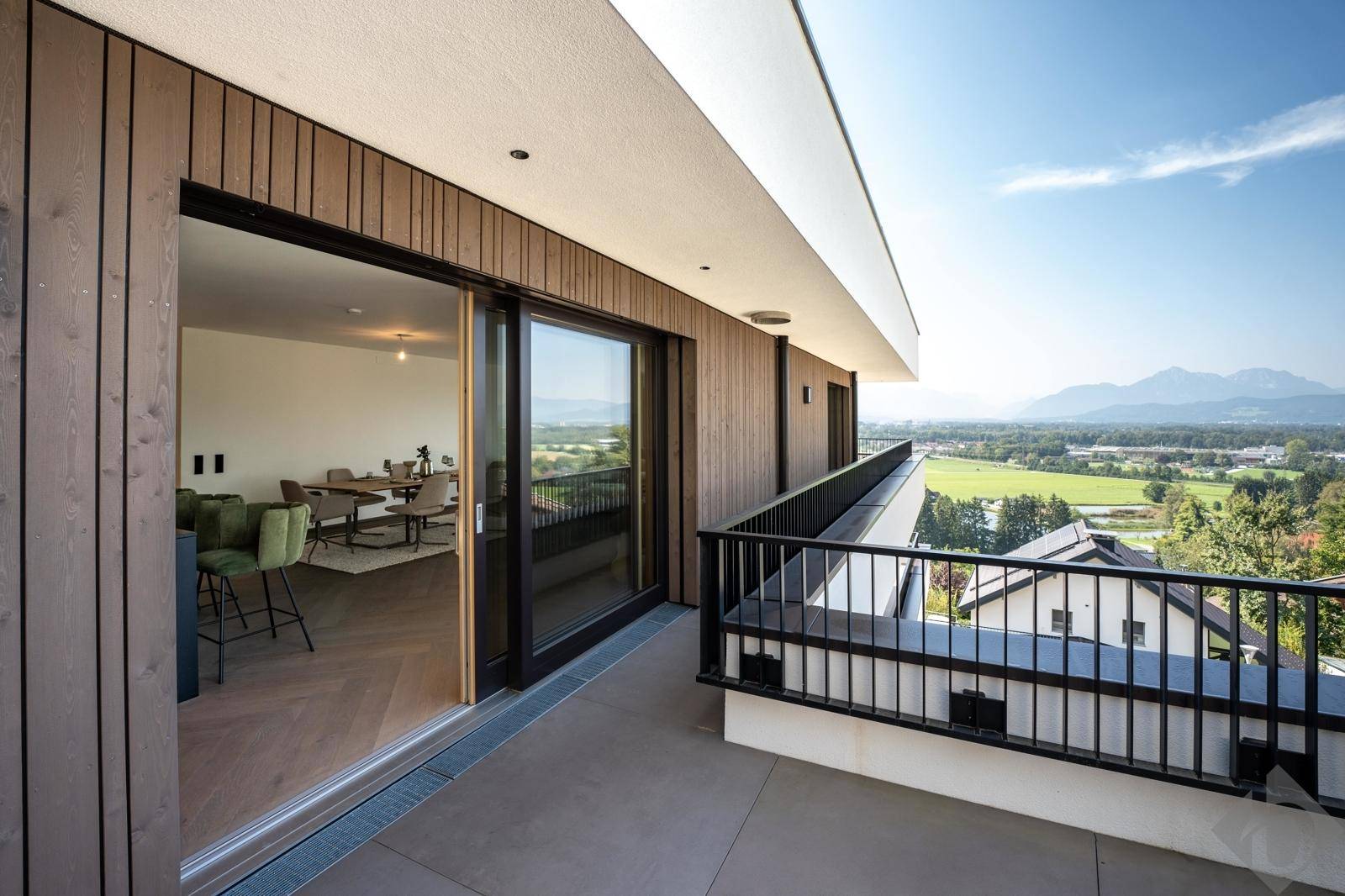Langer Balkon mit Holzwänden und Panoramablick auf die umliegende Landschaft und Berge.