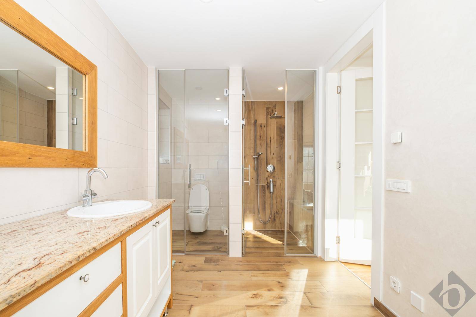 Modernes Badezimmer mit Duschen, Toilette und Waschtisch mit Granitplatte.