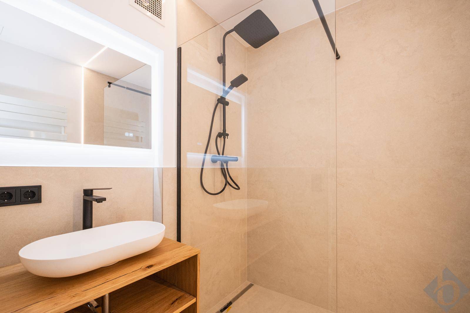 Modernes Badezimmer mit begehbarer Dusche, stilvollem Waschbecken und beleuchtetem Spiegel.