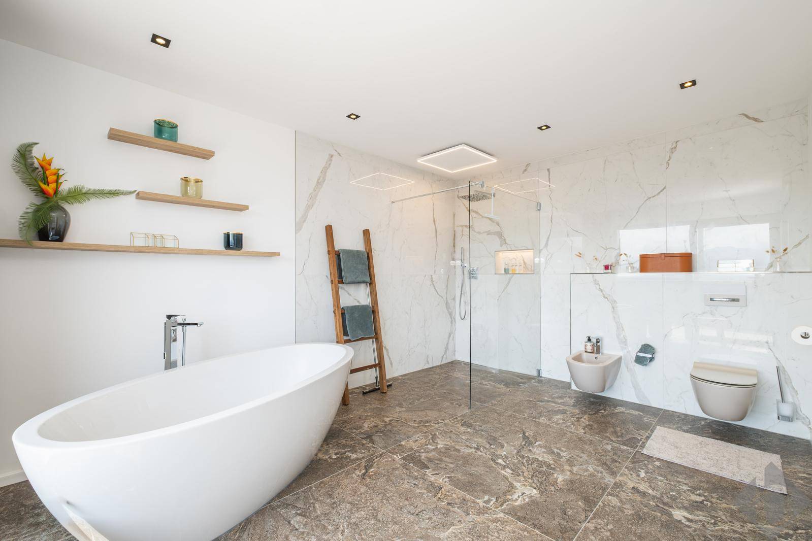 Luxuriöses Badezimmer mit freistehender Badewanne, großer Dusche und eleganten Marmorfliesen.