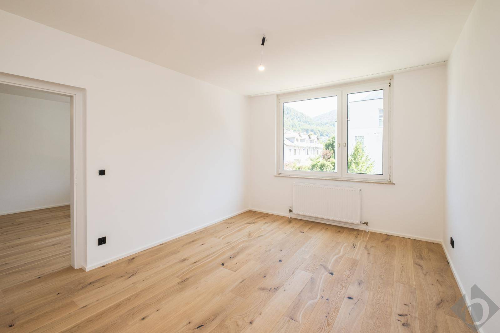 Geräumiges Schlafzimmer mit Eichenparkett, hellen Wänden und weitem Bergblick.