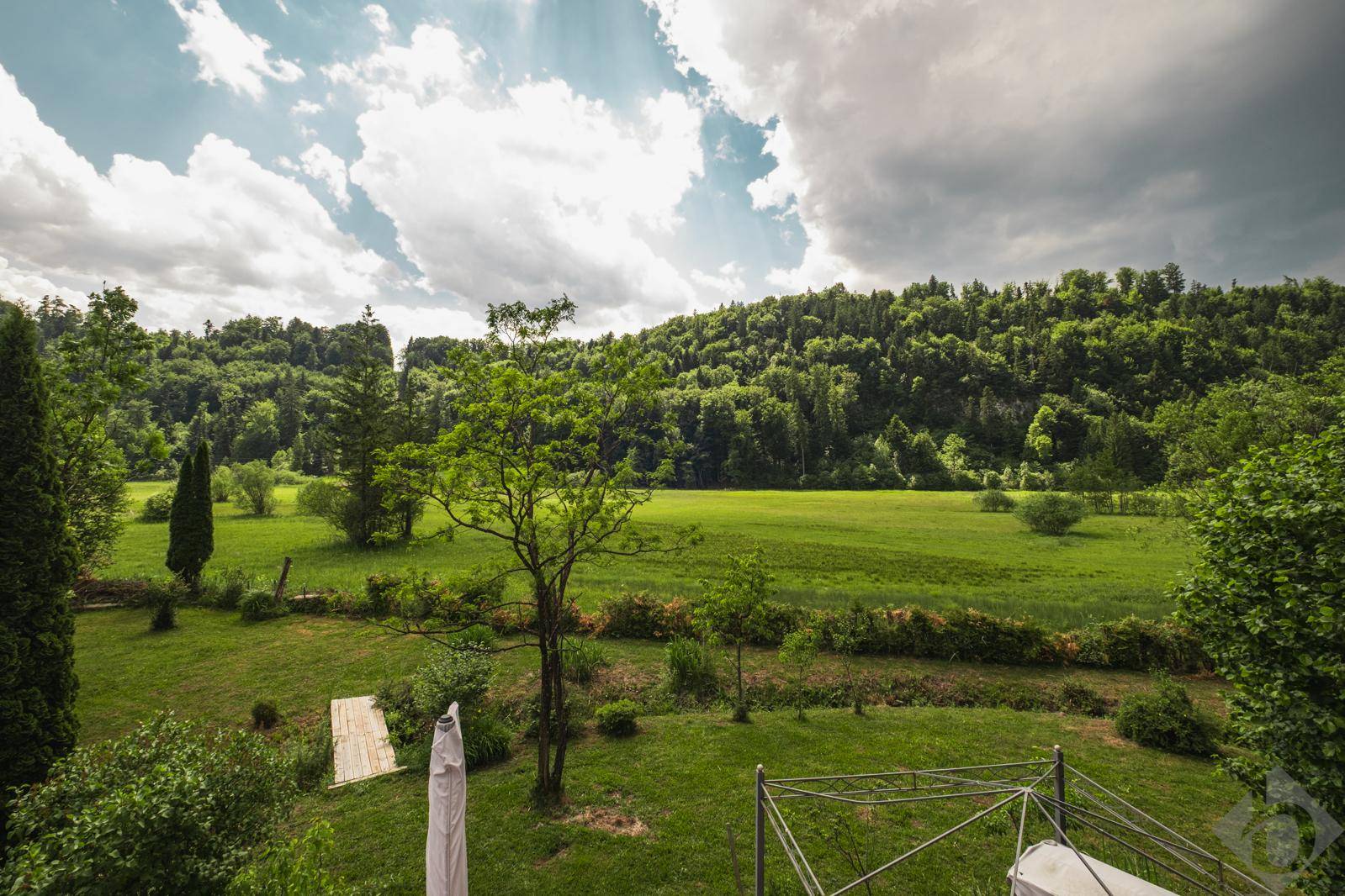 Weitläufiger Gartenbereich mit Blick auf grüne Wiesen, Wälder und die umliegende Landschaft.
