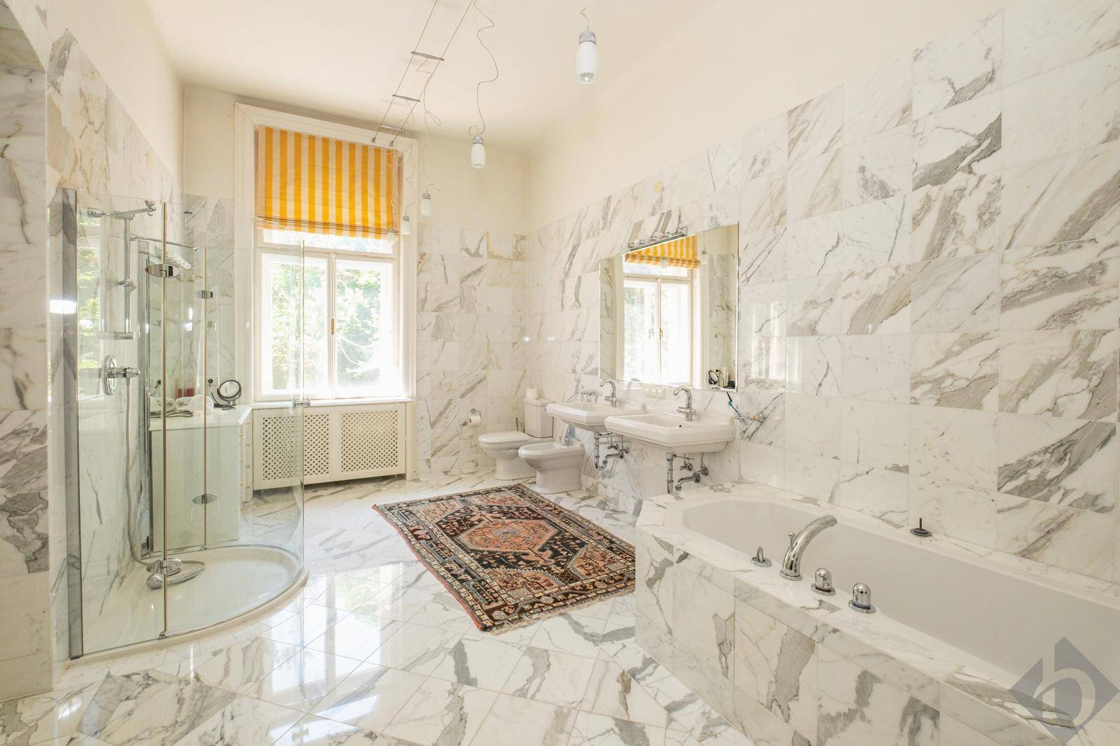 Luxuriöses Badezimmer mit Marmorfliesen, begehbarer Dusche, Badewanne und Doppelwaschbecken.