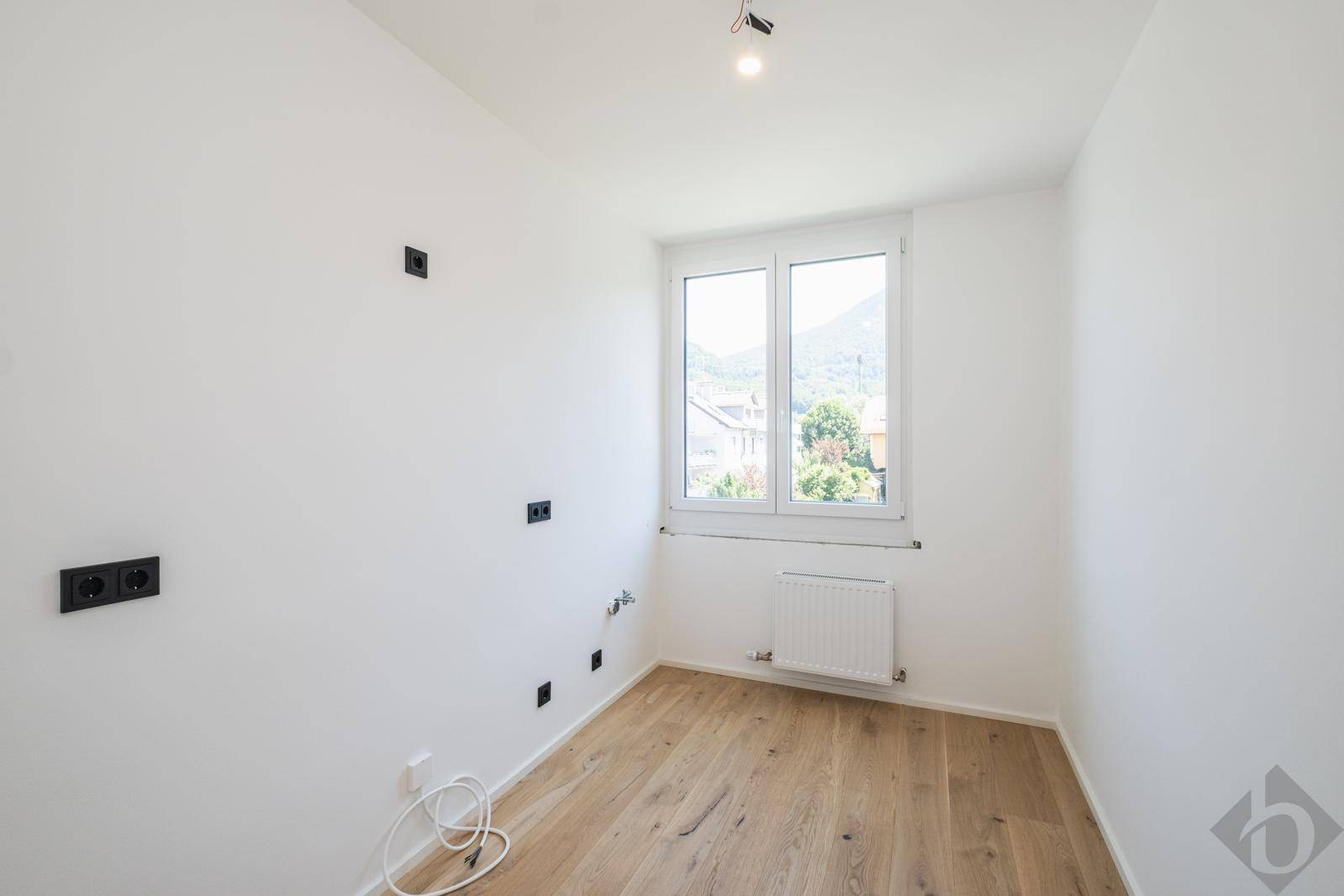 Helles Schlafzimmer mit Eichenparkett, weißen Wänden und Fenster mit Bergblick.