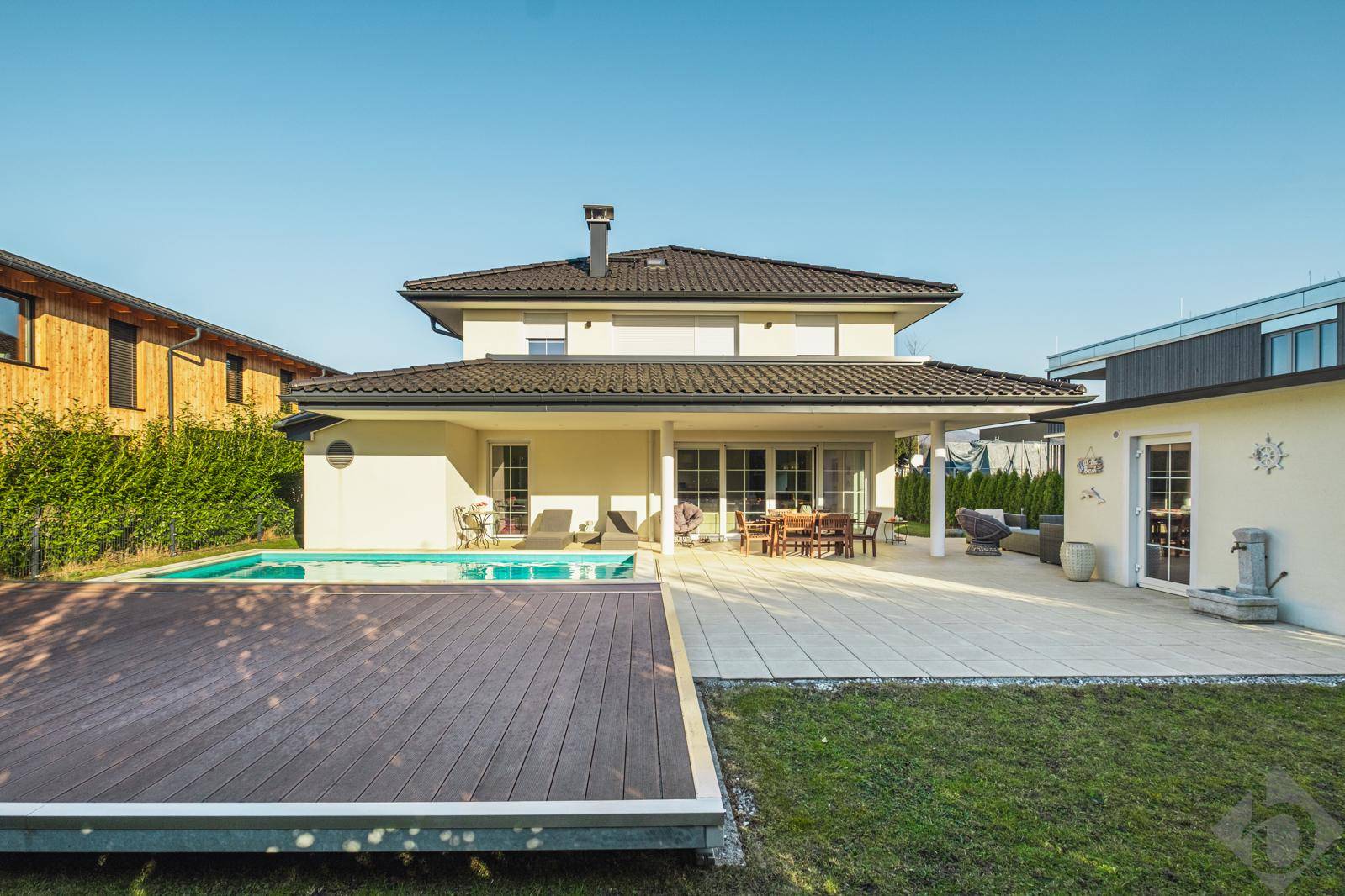 Großzügiger Gartenbereich mit Pool und weitläufiger Terrasse hinter dem modernen Haus.