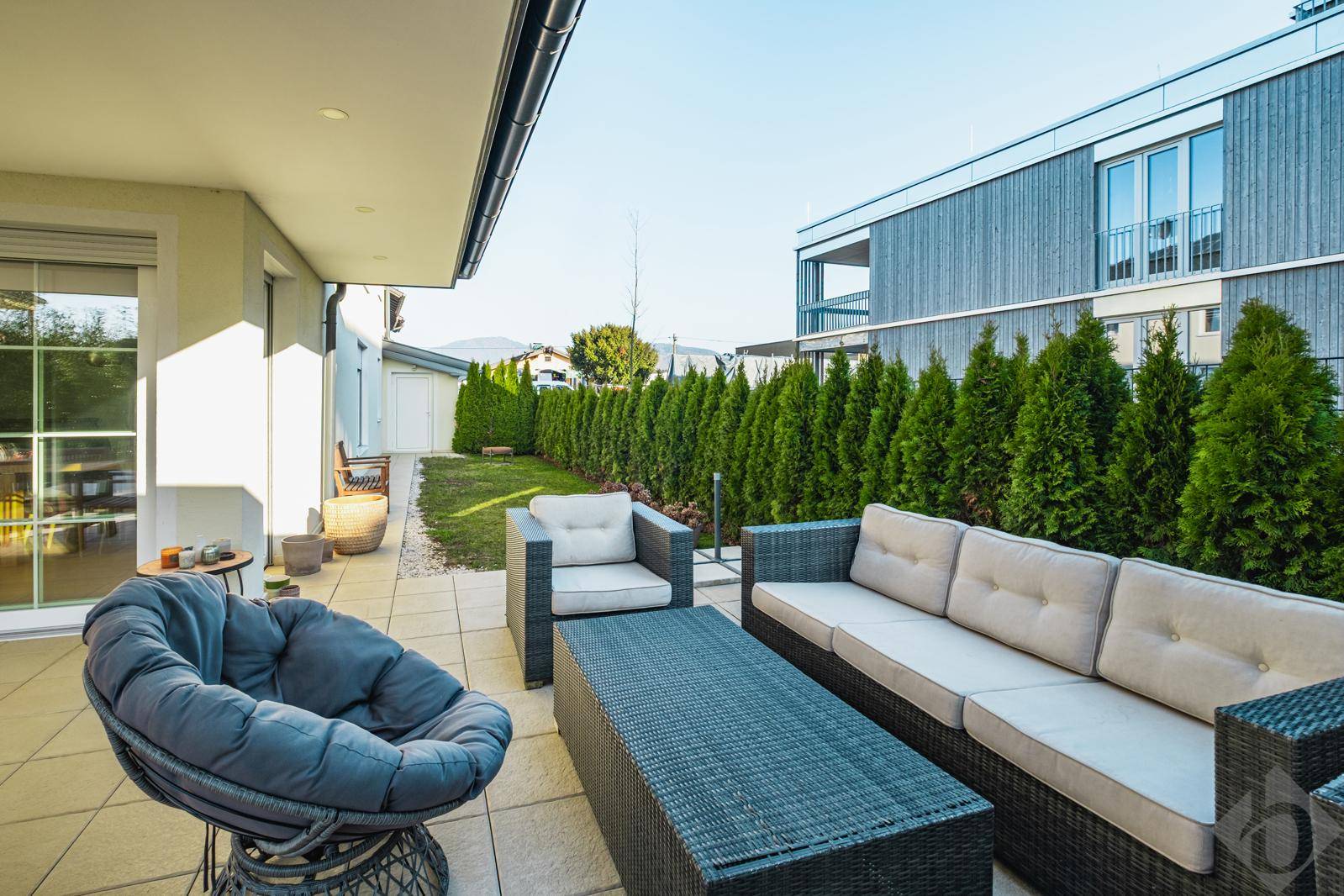 Gemütliche Terrasse mit modernen Gartenmöbeln und hoher Hecke für Privatsphäre.