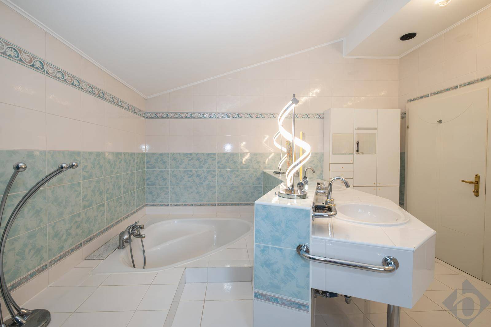 Badezimmer mit eingebauter Badewanne, Einzelwaschbecken und hellblauen Fliesen.