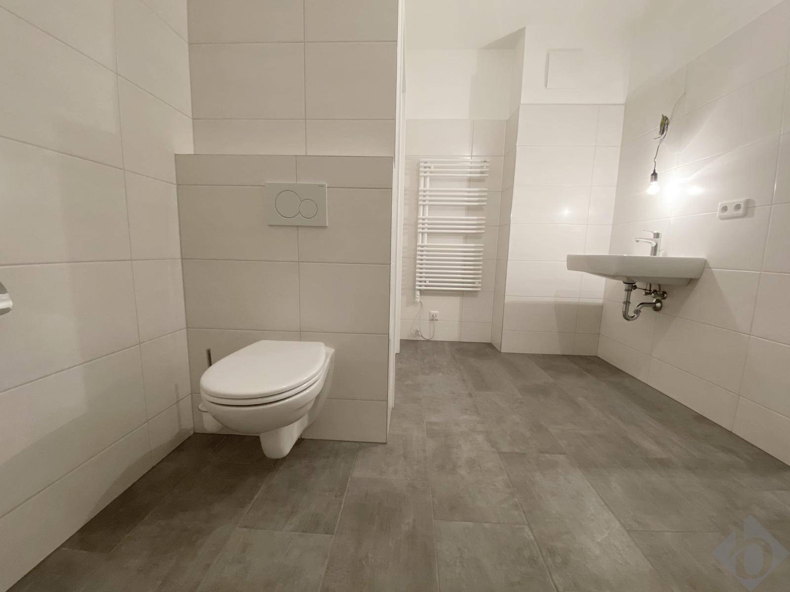 Modernes Badezimmer mit weißen Wandfliesen, grauen Bodenfliesen und wandhängendem WC.