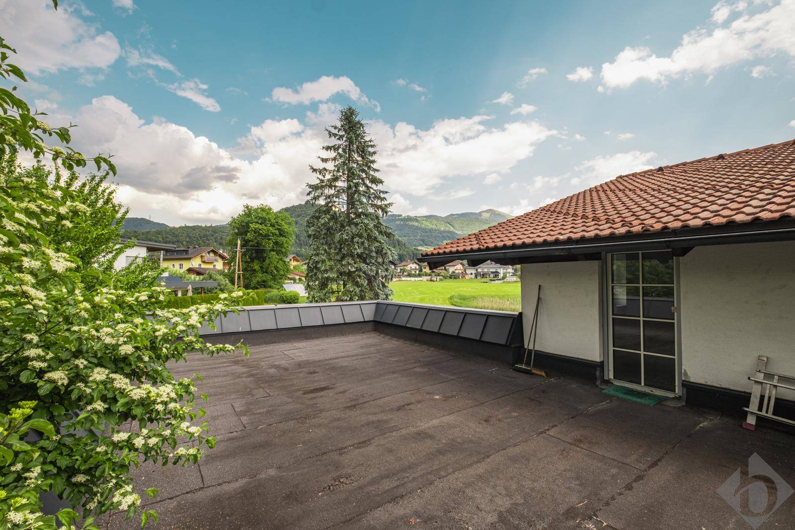 Geräumige Dachterrasse mit weitem Blick auf die grüne Landschaft und die Berge.