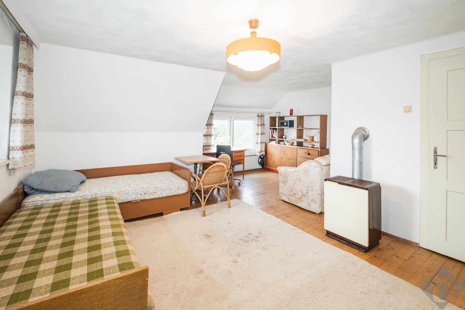 Helles Schlafzimmer im Dachgeschoss mit schrägen Decken, Holzboden und einem gemütlichen Bett.