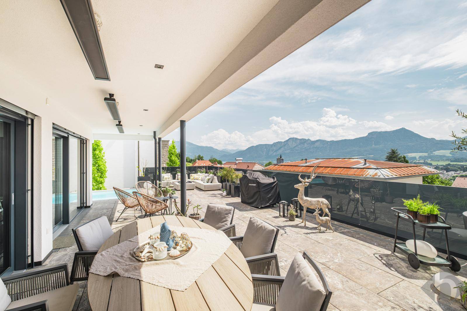 Geräumige überdachte Terrasse mit Essbereich, Lounge und weitem Blick auf die umliegenden Berge.