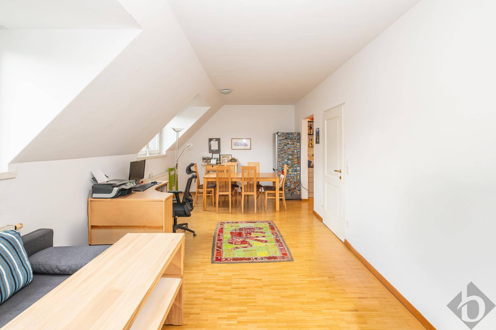 Heller offener Wohnbereich mit Holzboden, Dachschrägen und Platz für Ess- und Arbeitsbereich.