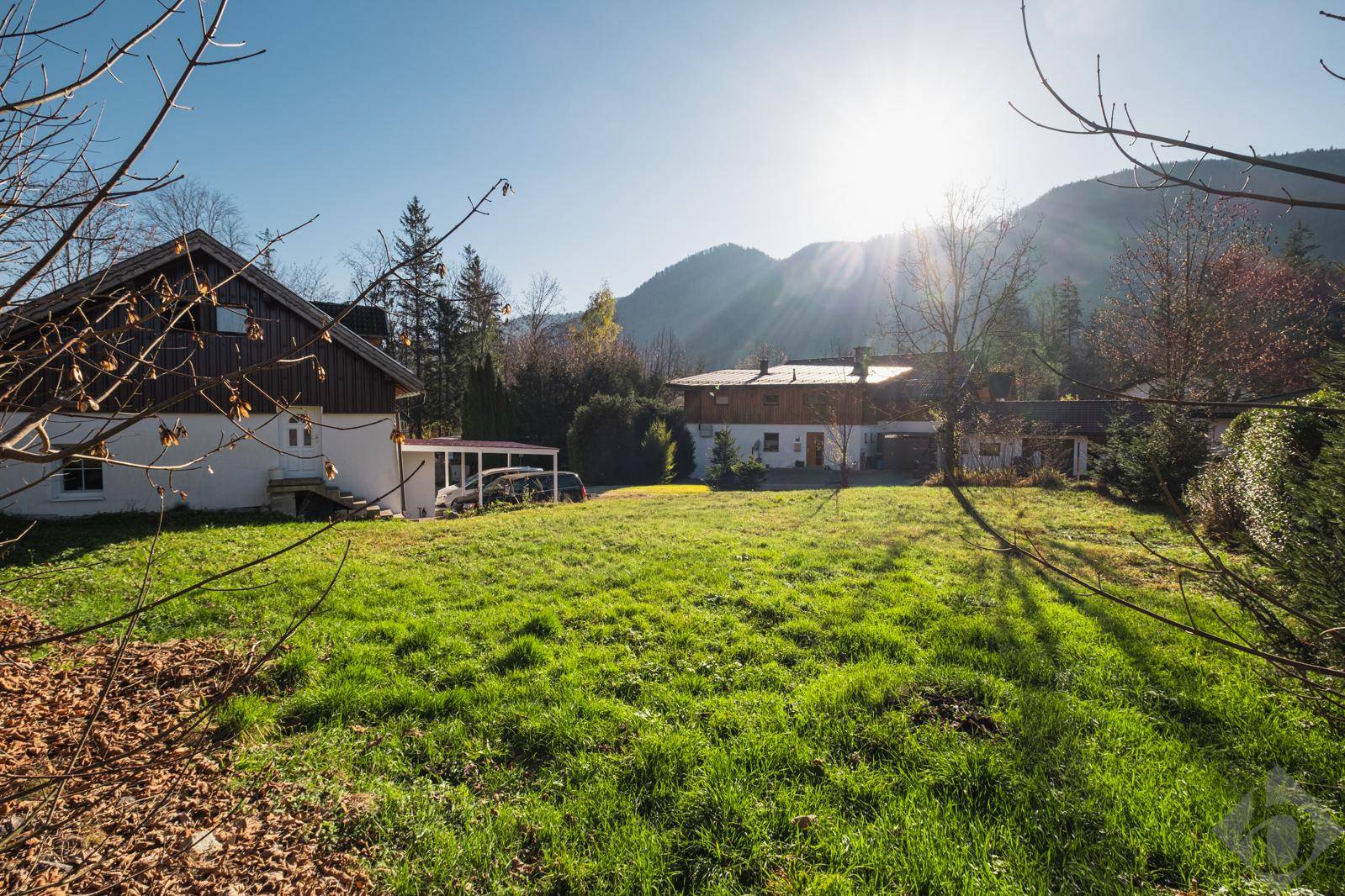 Weitläufige Rasenfläche mit Blick auf umliegende Häuser und die sonnenbeschienenen Berge.