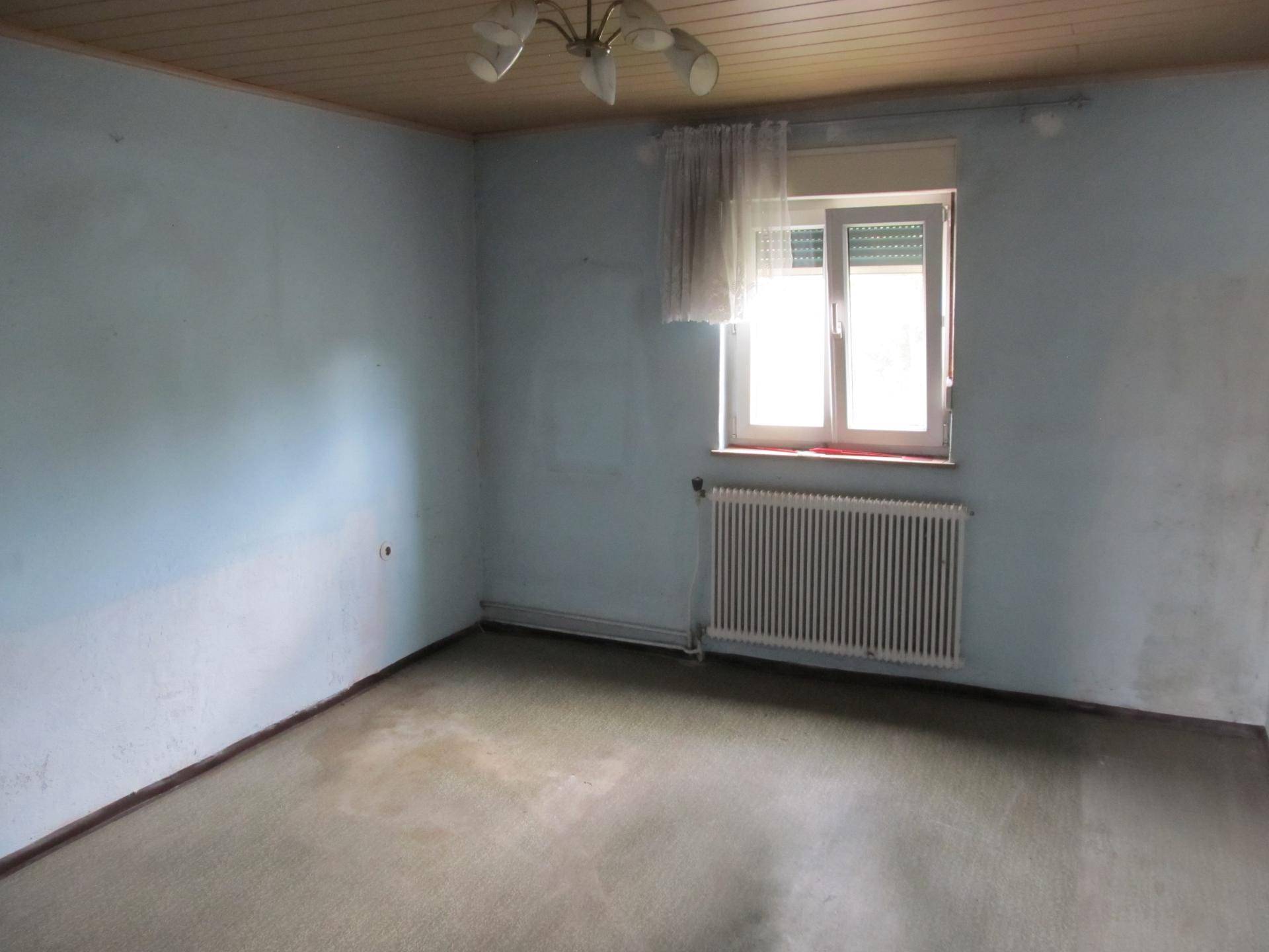 Schlafzimmer mit blauen Wänden, Holzdecke, Teppichboden und einem Fenster mit Heizkörper.