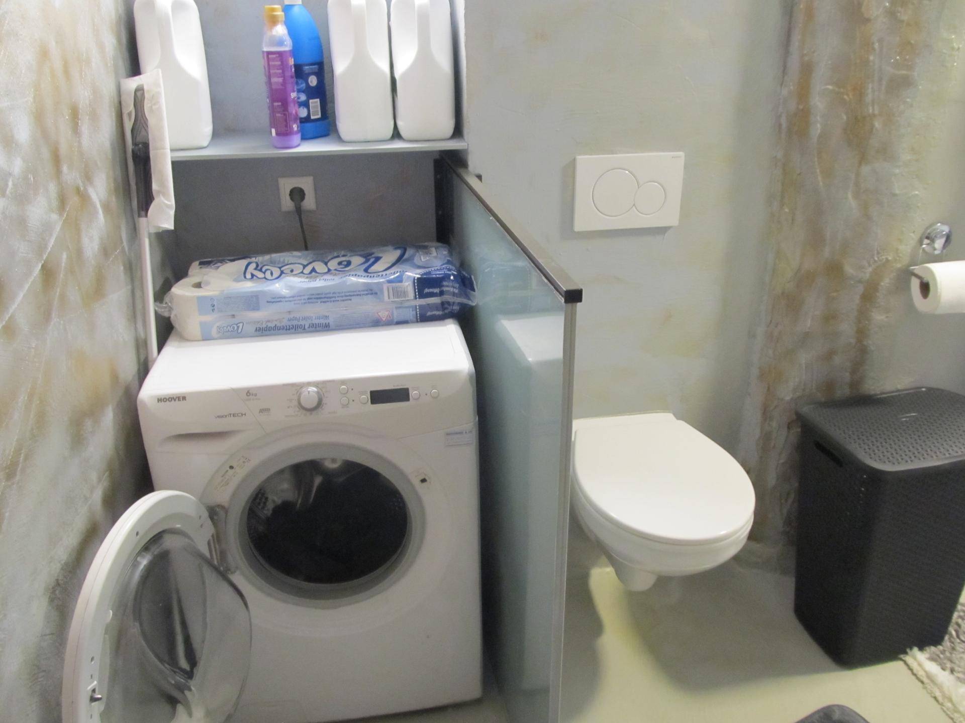 Waschmaschinenbereich mit Wand-WC und Ablagemöglichkeiten.