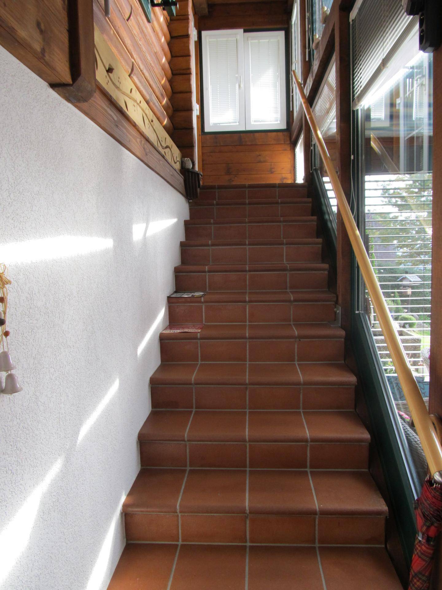 Geflieste Treppe mit Holzgeländer, die zu den oberen Etagen führt.