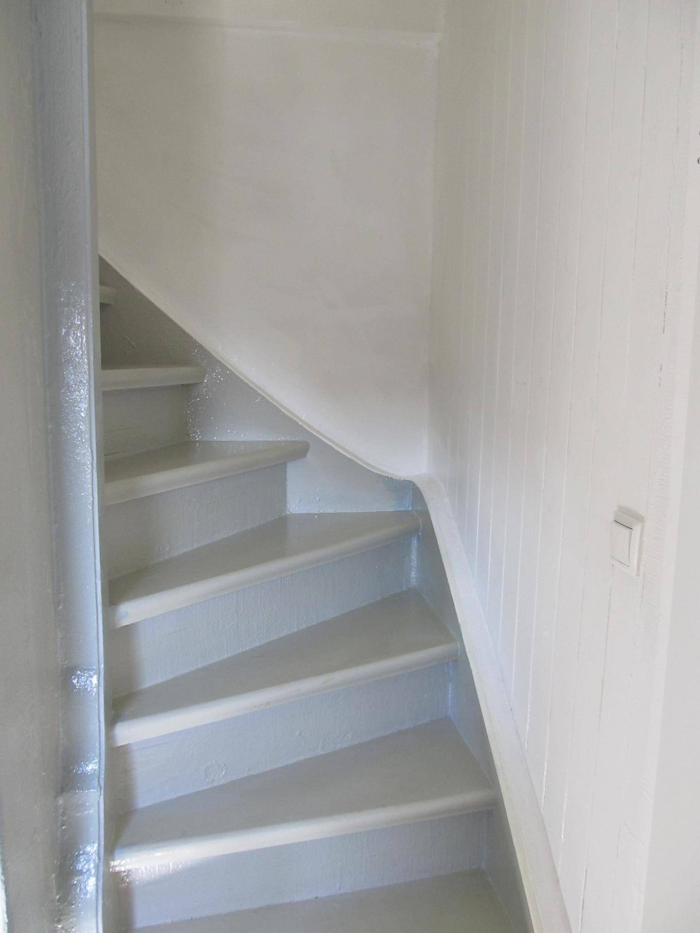 Weiß gestrichene Holztreppe, die in die obere Etage führt.