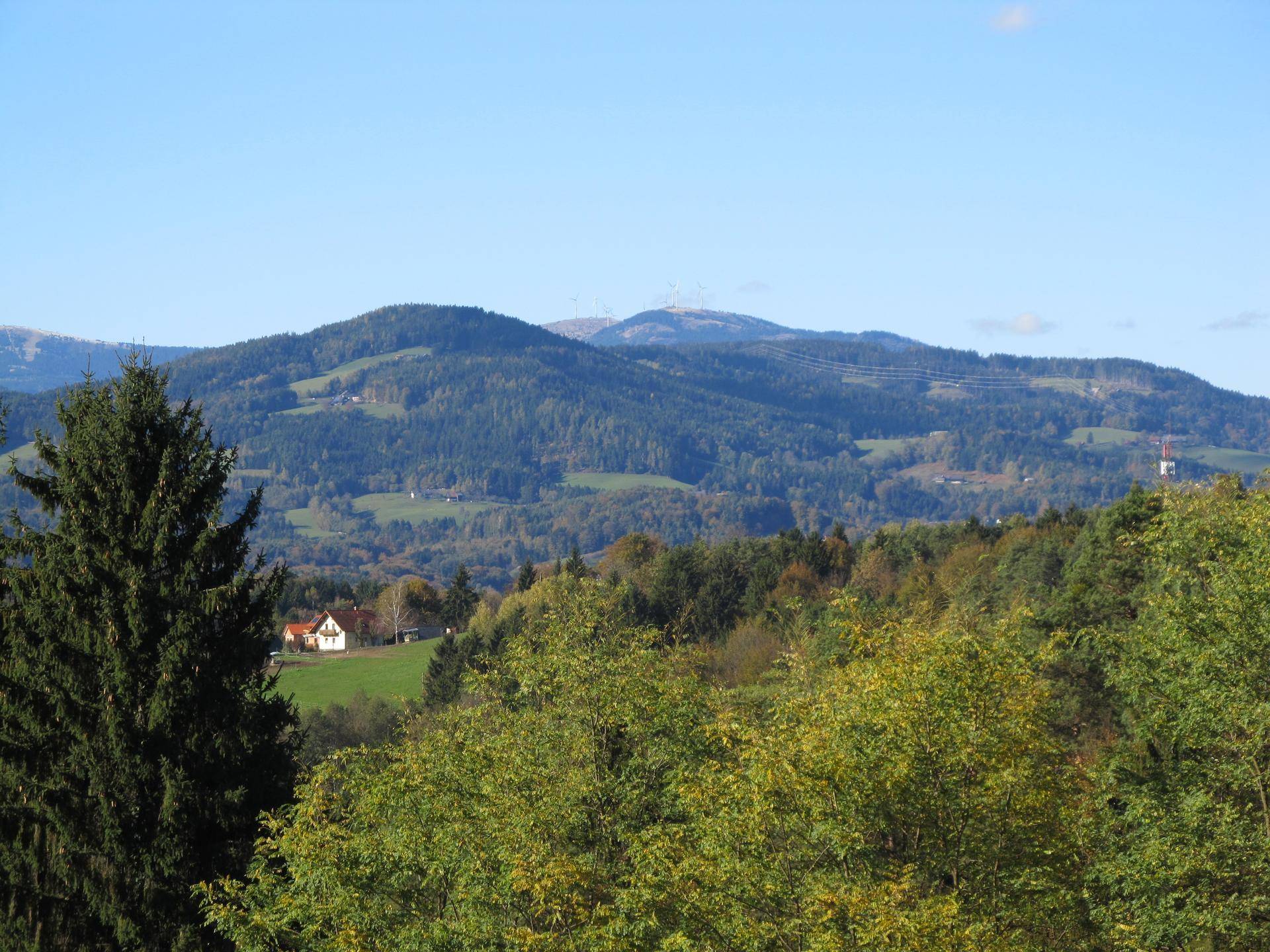 Weitläufiger Blick über bewaldete Hügel und Täler mit einem Haus in der Ferne.