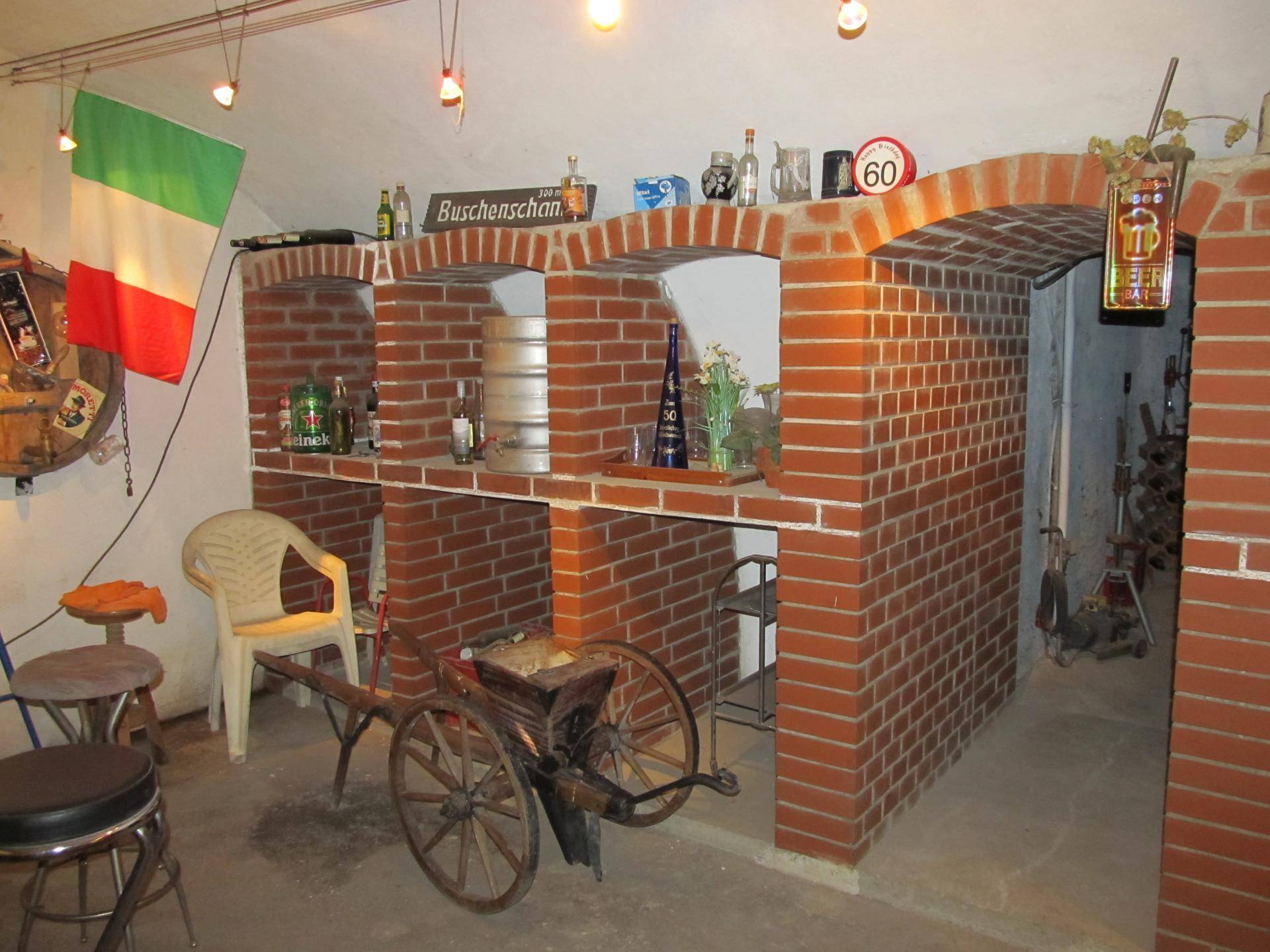 Weiterer Blick in den Kellerraum mit Ziegelbögen, italienischer Flagge und rustikalen Dekorationen.