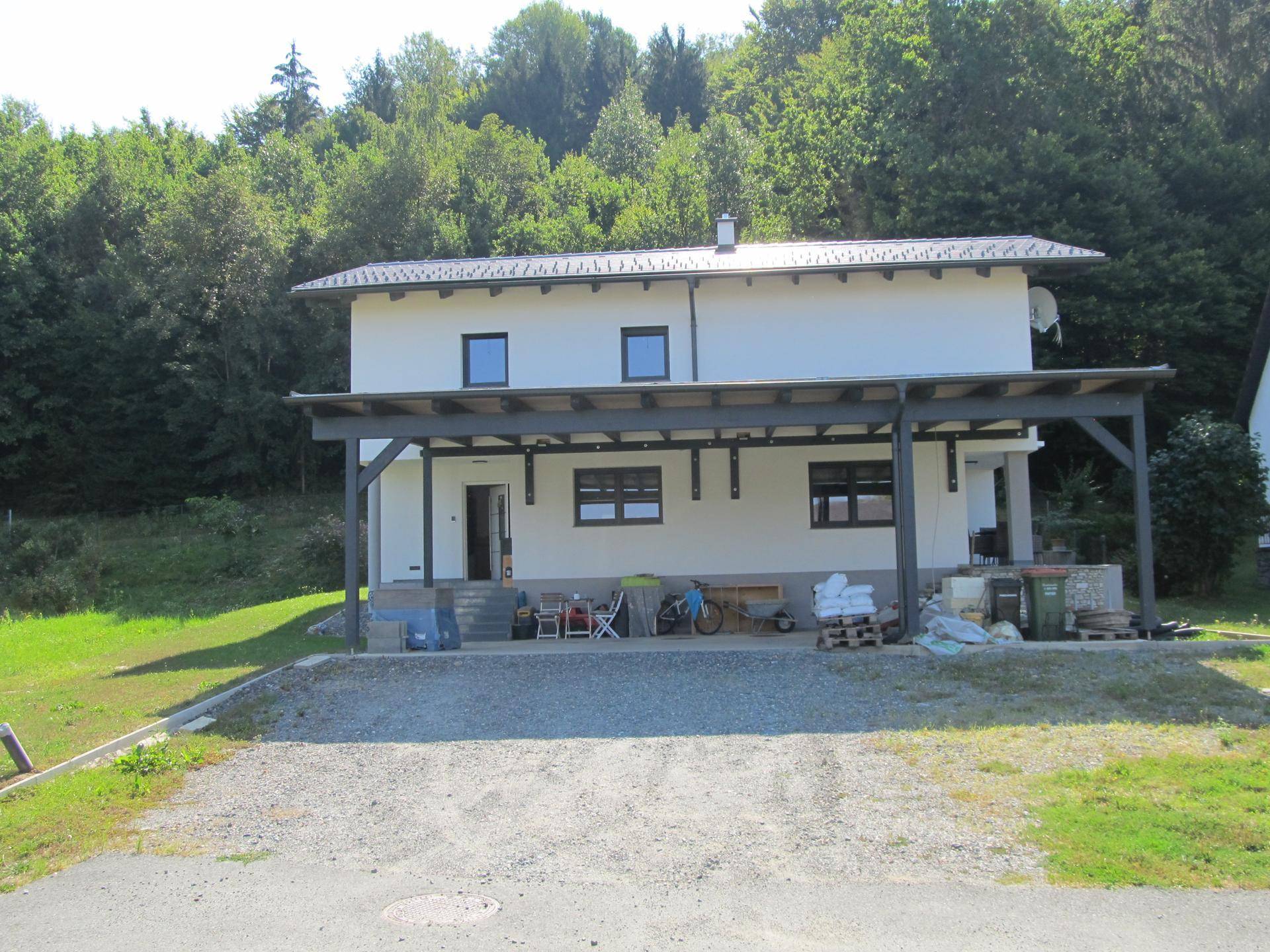 Vorderansicht des Einfamilienhauses mit großem Carport und heller Fassade.
