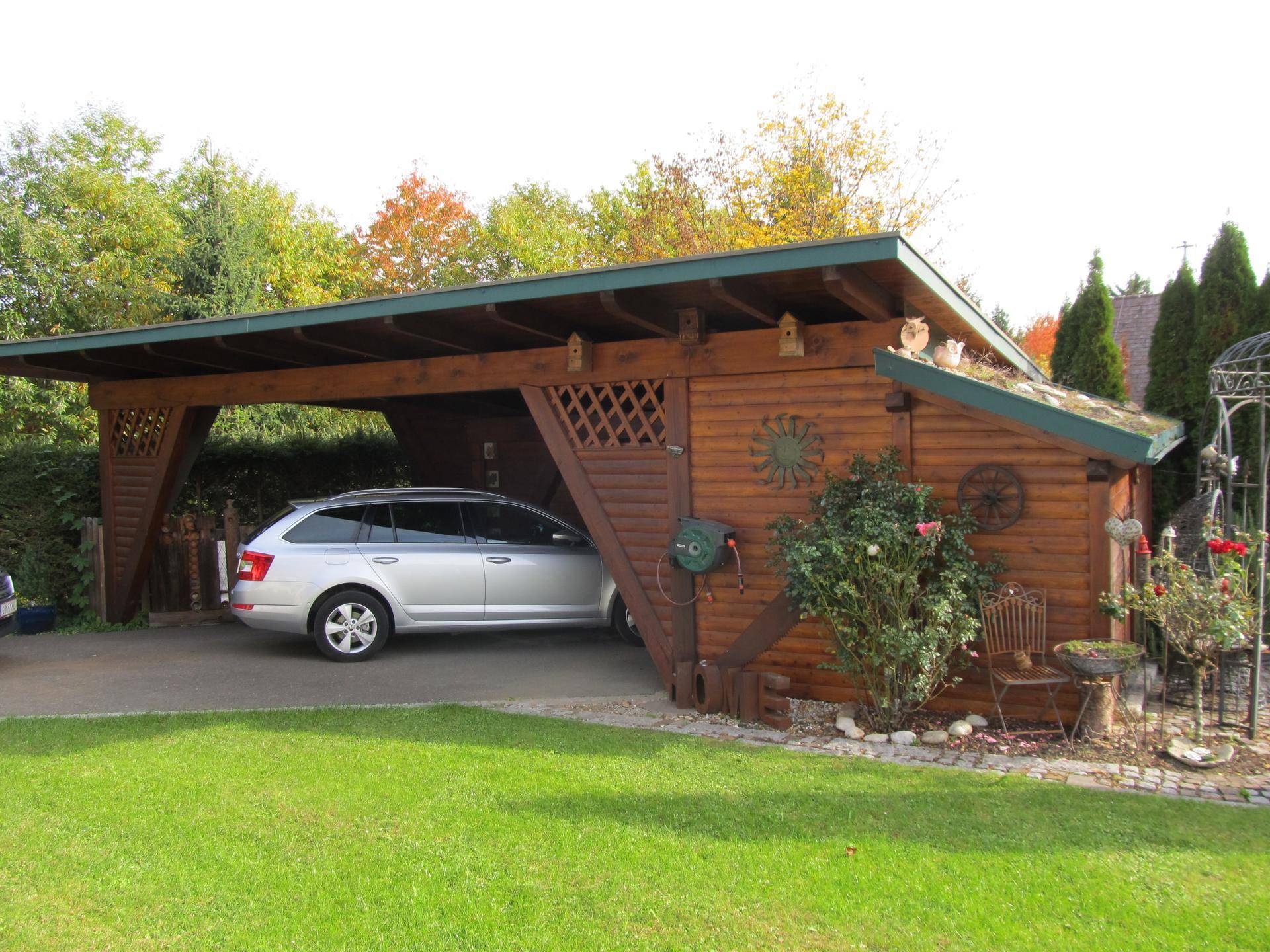 Holzcarport mit einem geparkten Auto und einem angrenzenden Holzschuppen.