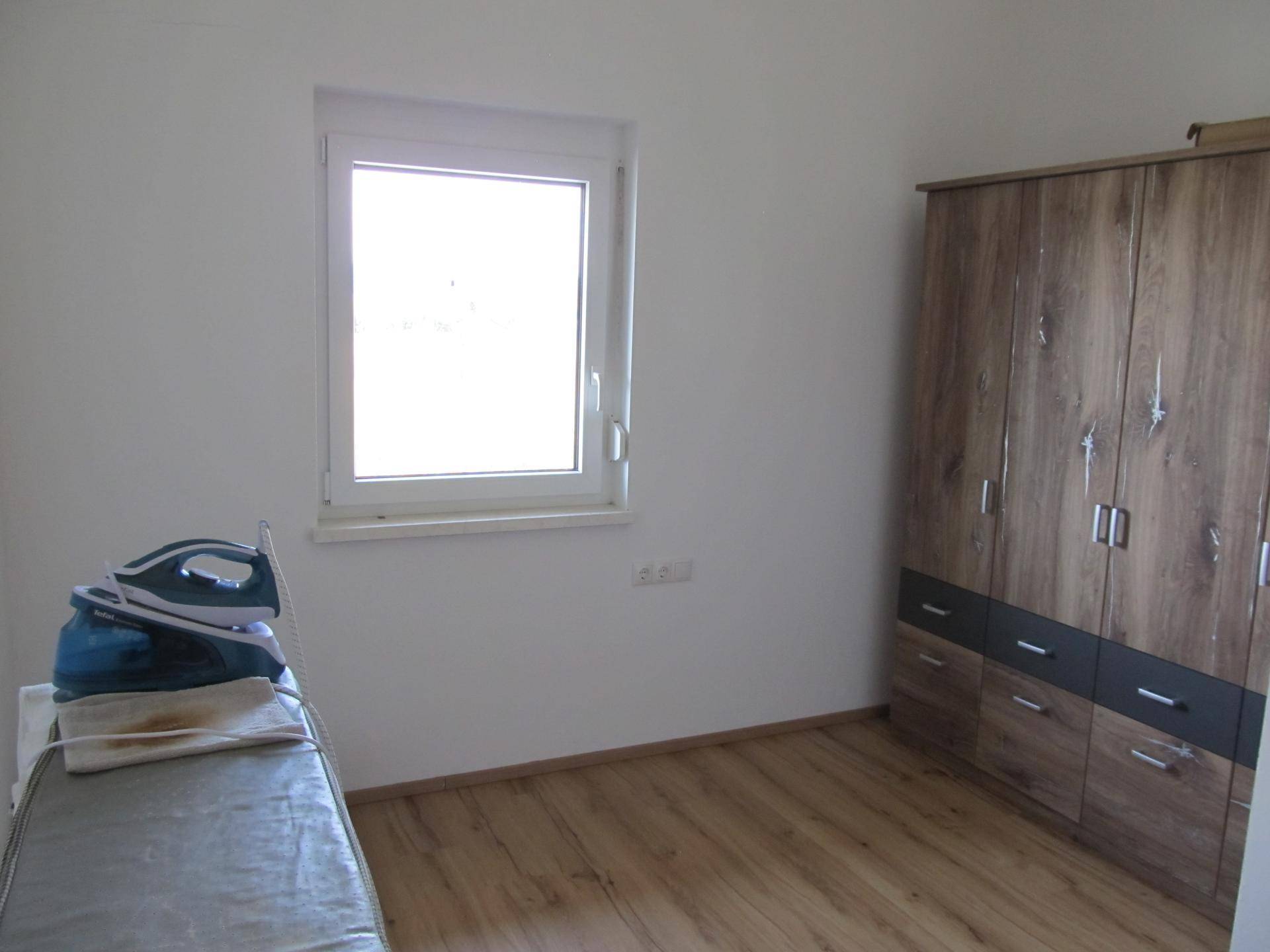 Helles Zimmer mit Holzfußboden und einem großen Kleiderschrank, ideal als Schlaf- oder Gästezimmer.
