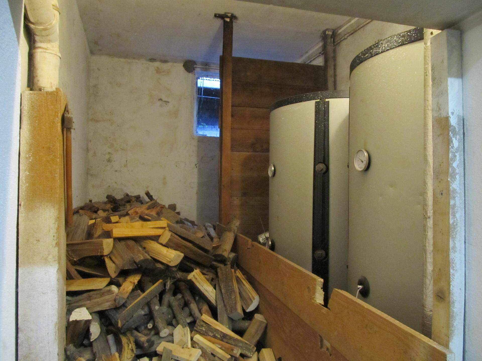 Hauswirtschaftsraum mit großen Warmwasserspeichern und einem Vorrat an Brennholz.