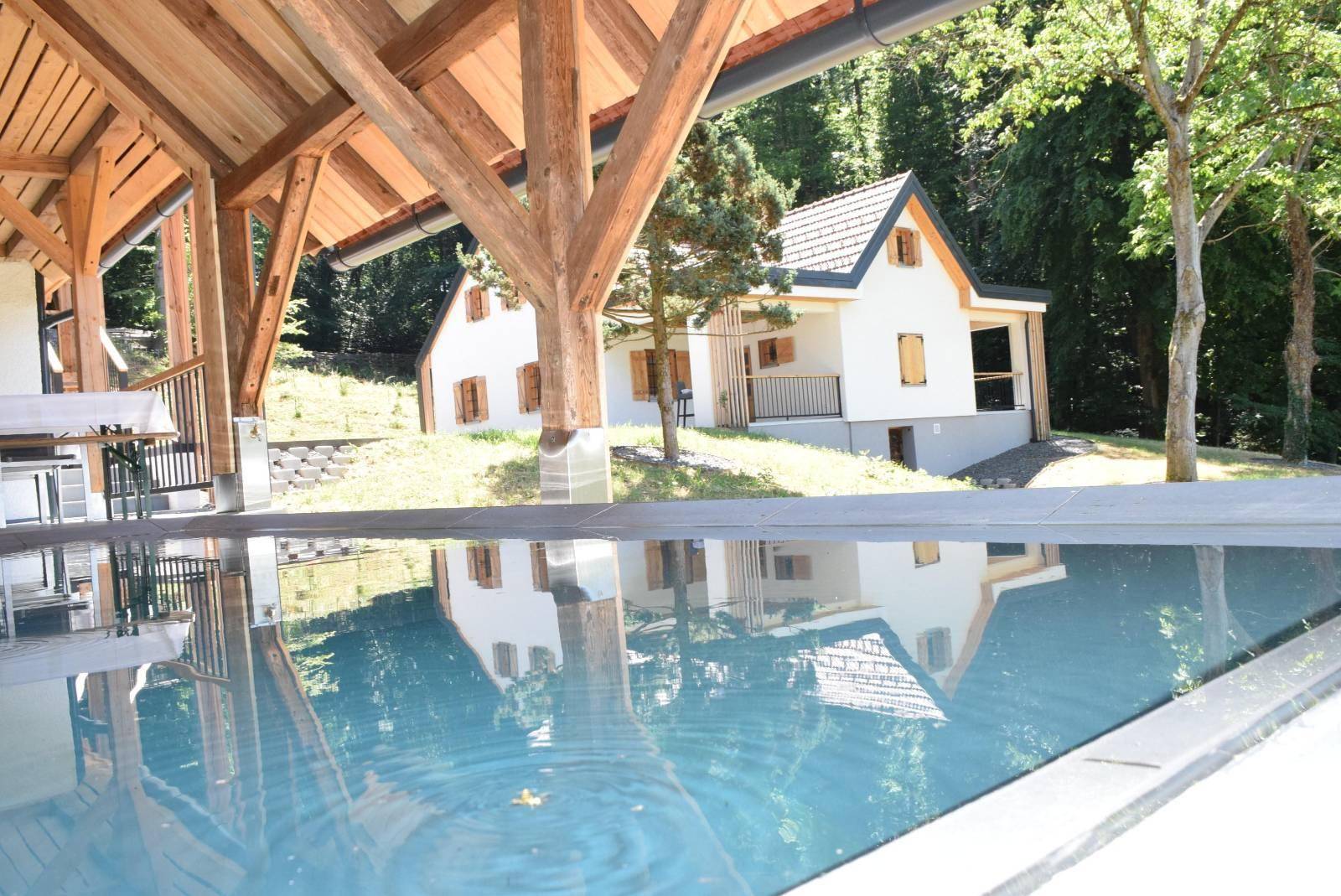 Einladender Außenpool mit Holzkonstruktion und Blick auf weitere Chalets in der Natur.
