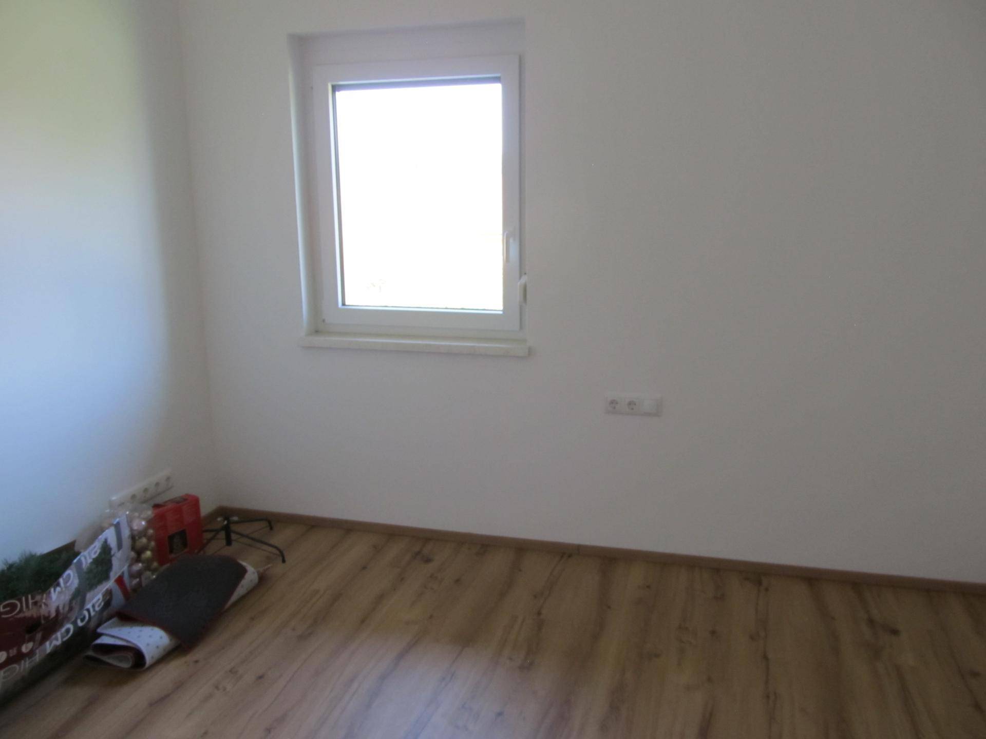 Helles Schlafzimmer mit Laminatboden und einem großen Fenster für viel Tageslicht.