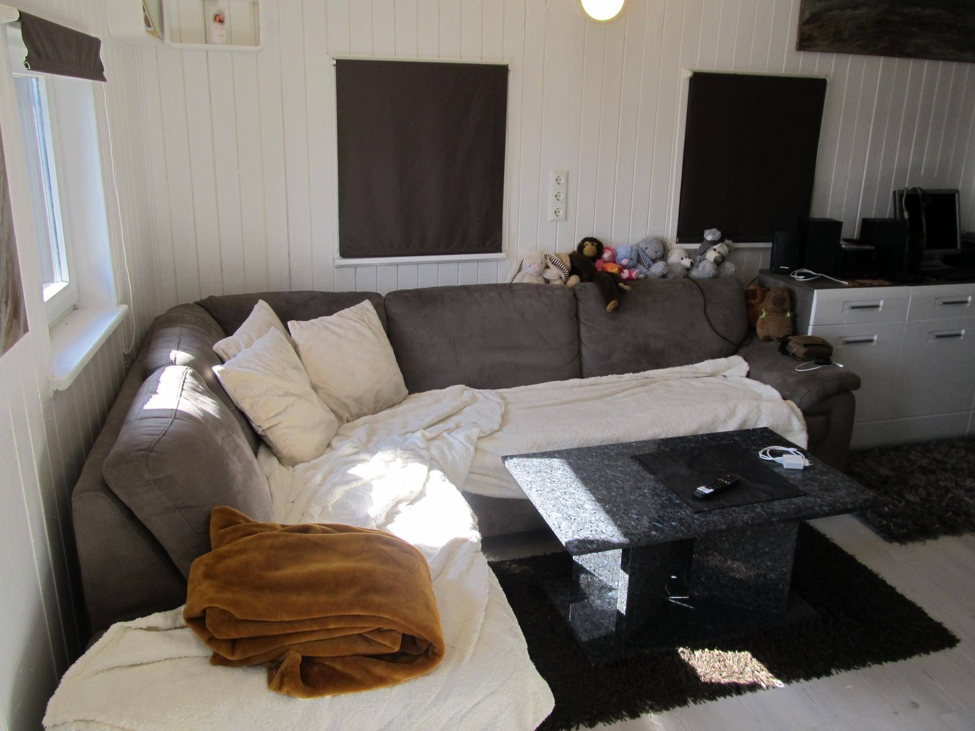 Gemütliches Wohnzimmer mit großem Sofa, Couchtisch und Holzpaneelen an den Wänden.