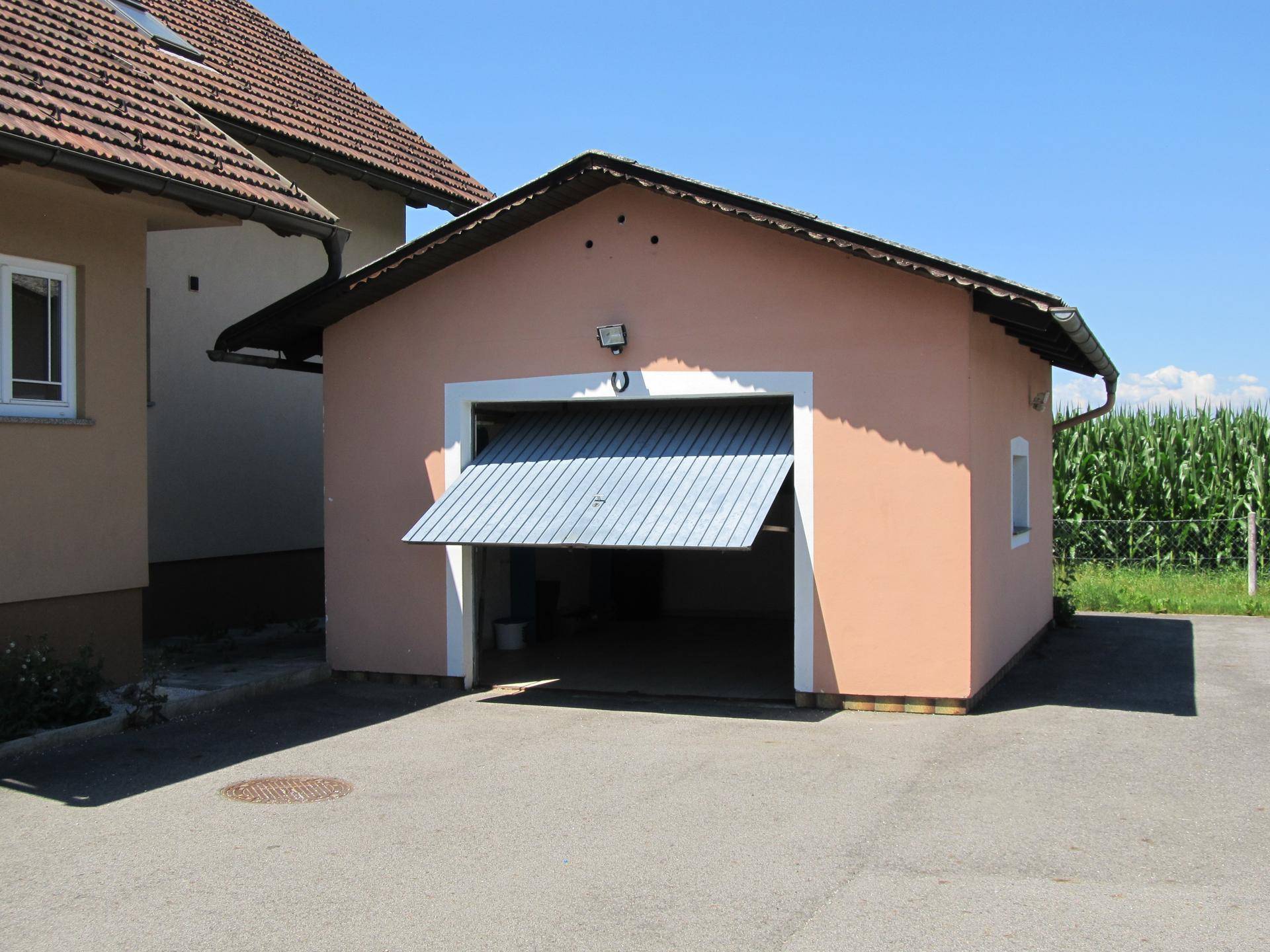 Separate Garage mit geöffnetem Tor und gepflastertem Vorplatz neben dem Wohnhaus.