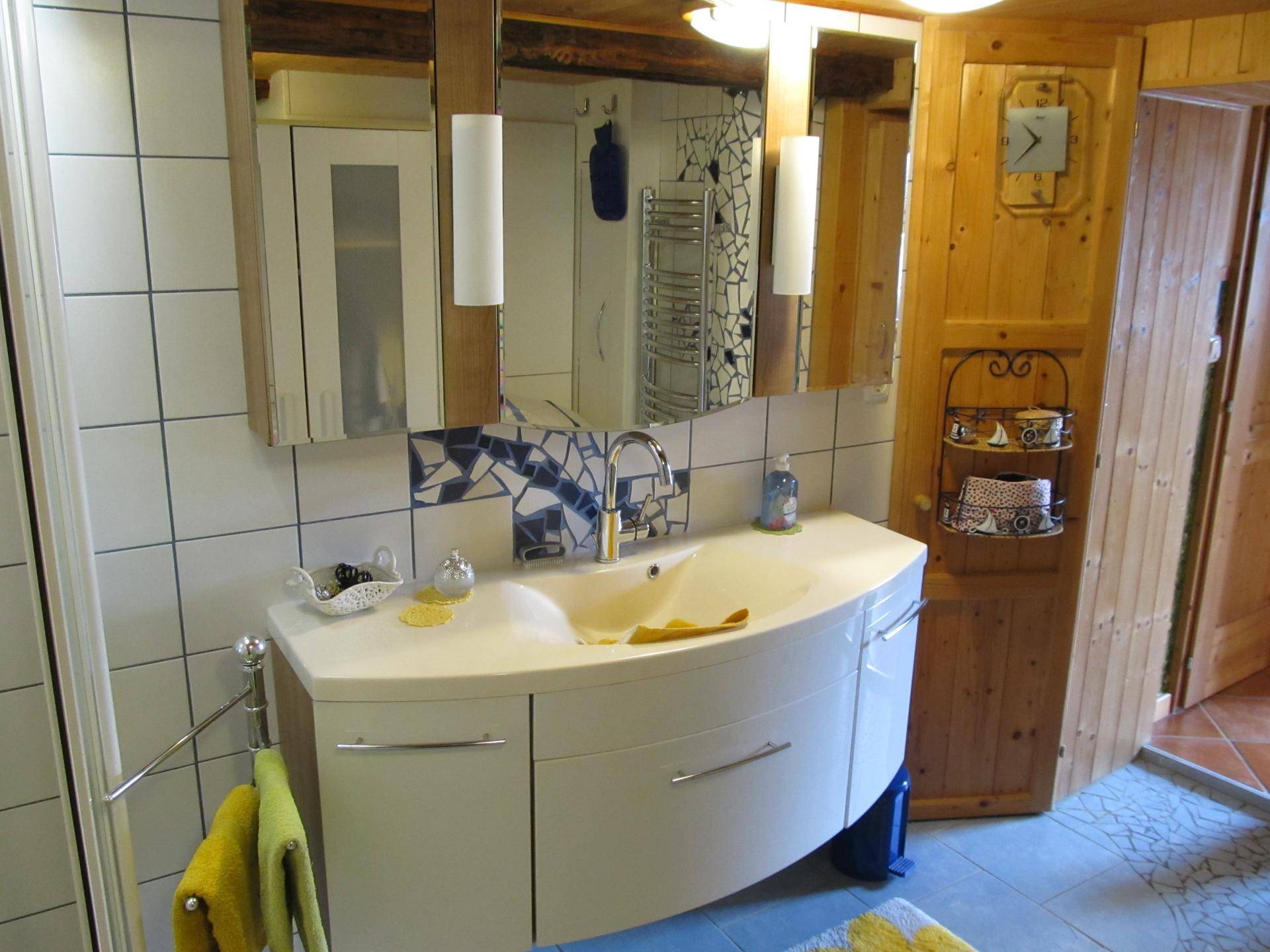 Badezimmer mit modernem Waschtisch, großem Spiegel und Holzvertäfelung.