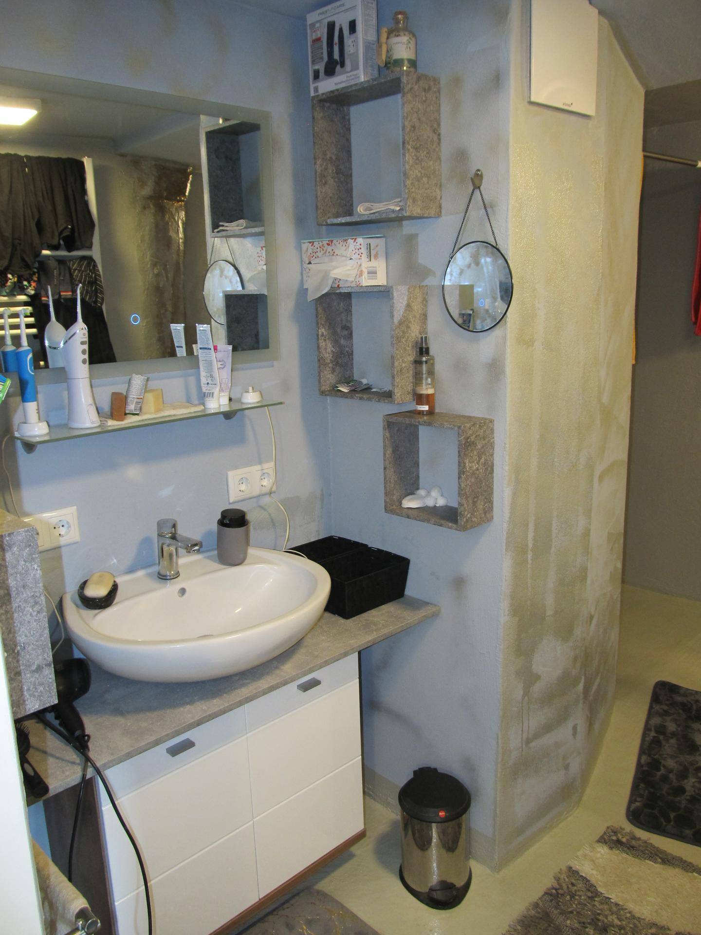 Modernes Badezimmer mit Waschbecken, Spiegel und strukturierten Wänden.