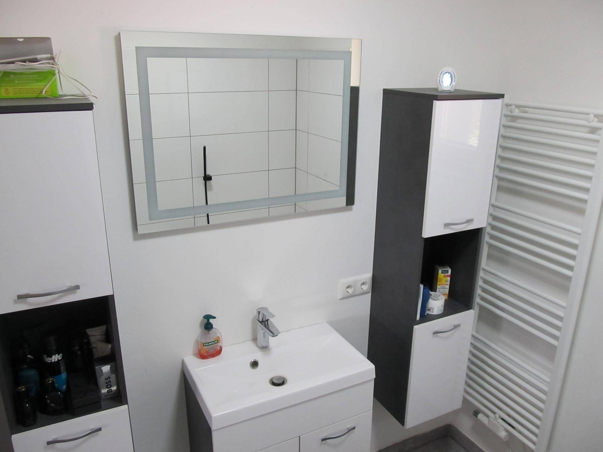 Helles Badezimmer mit modernem Waschtisch, Spiegelschrank und weißen Fliesen.