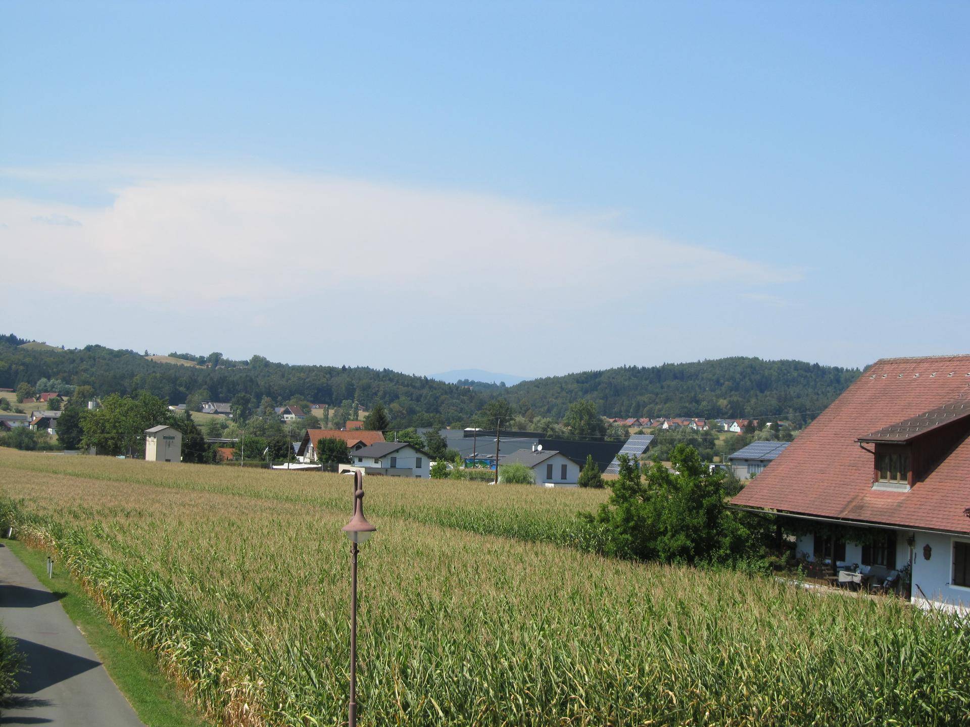 Panoramablick über weite Felder und eine ländliche Siedlung unter blauem Himmel.