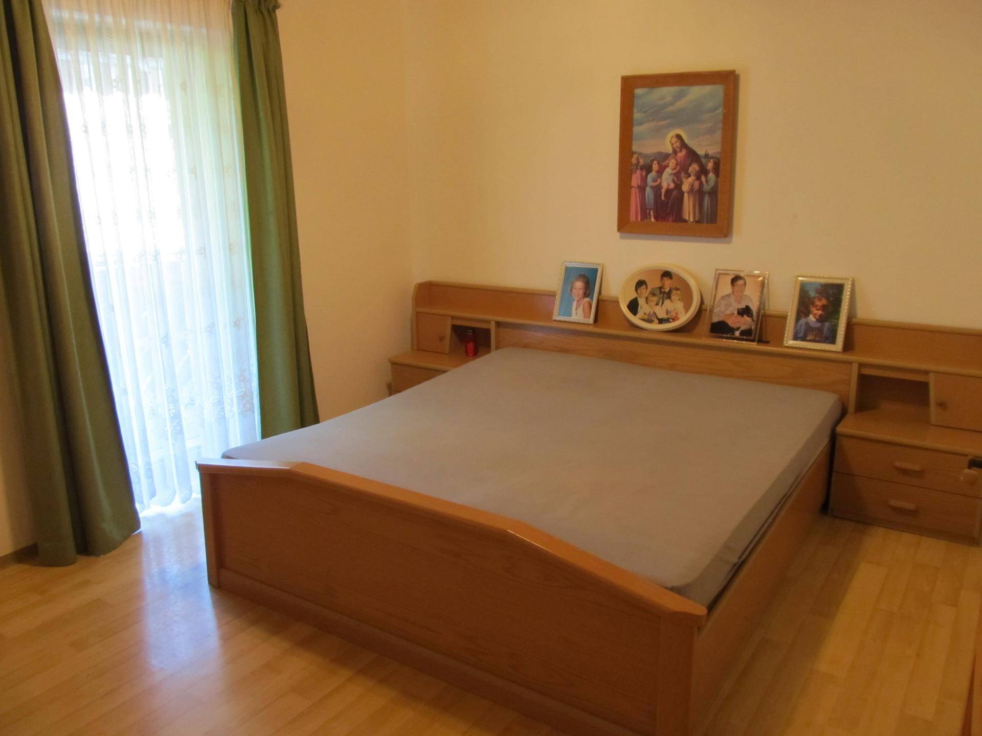 Schlafzimmer mit Doppelbett, Holzmöbeln und Parkettboden, hell und freundlich.