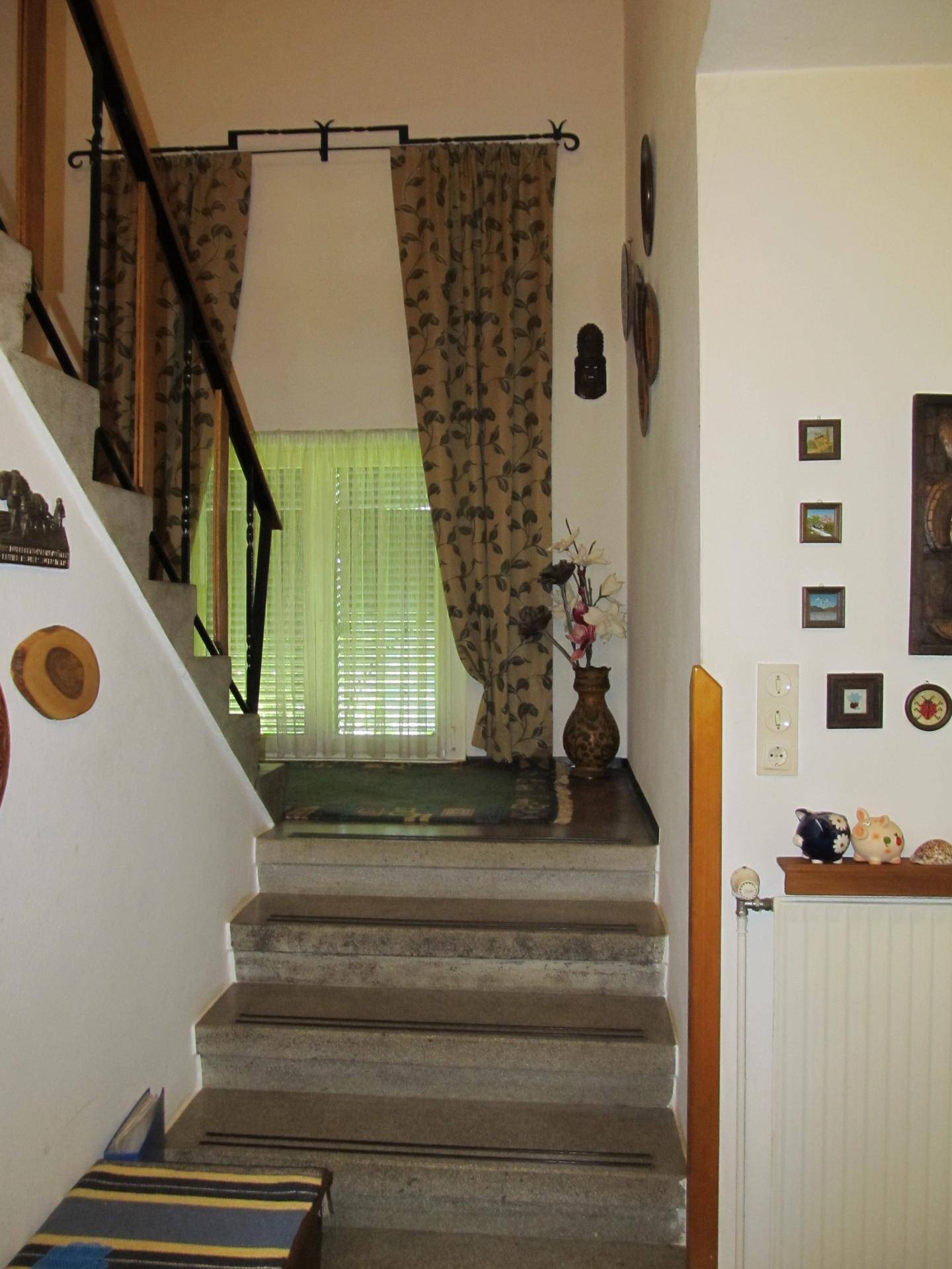 Treppenhaus mit Steinstufen und einem Fenster, das natürliches Licht in den Flur bringt.