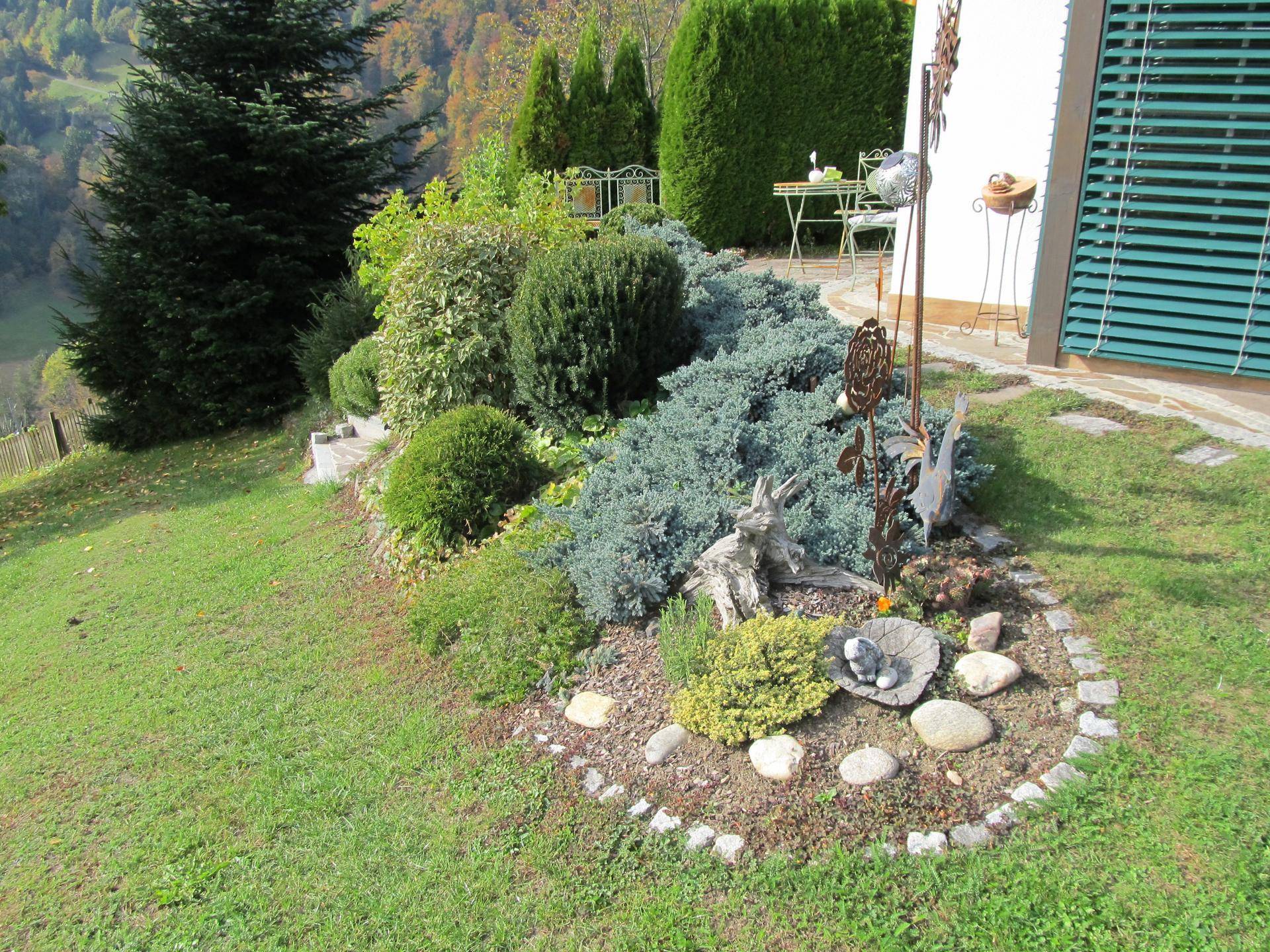 Liebevoll angelegter Gartenbereich mit Steinen, verschiedenen Pflanzen und Rasenflächen.