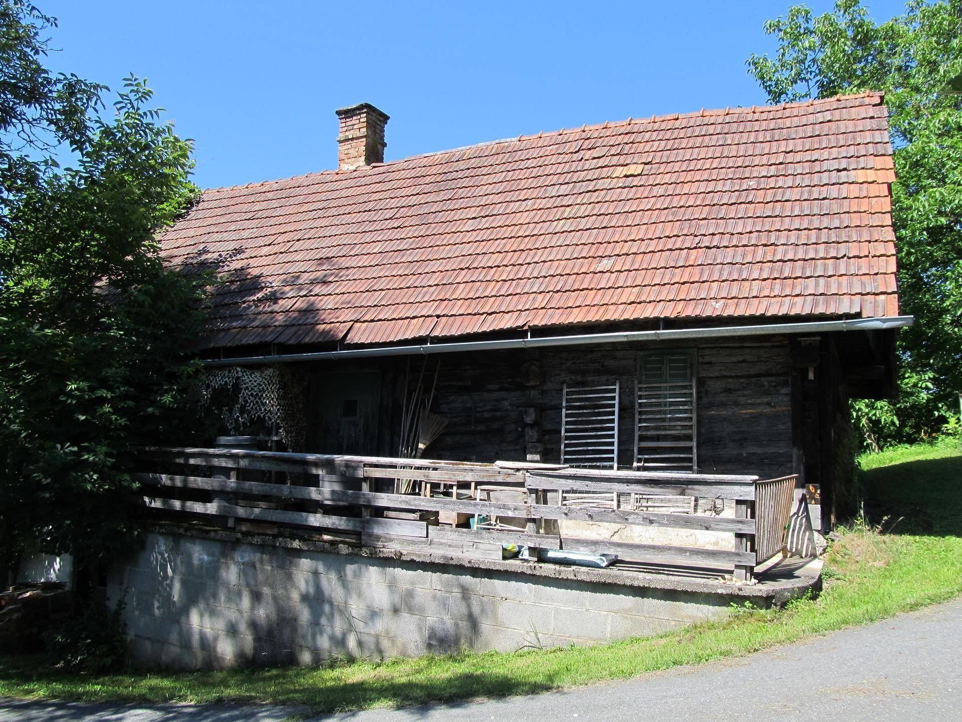 Rustikales Holzgebäude mit Ziegeldach und einer einfachen Holzveranda im ländlichen Stil.