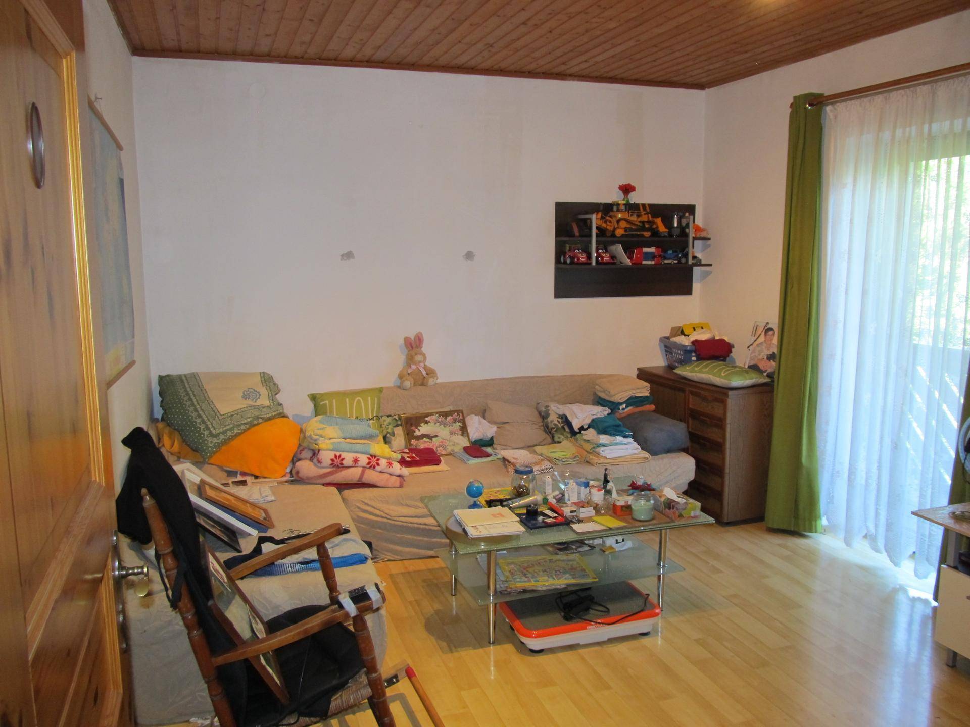Wohnzimmer mit Sofa, Couchtisch und Parkettboden, mit Zugang zum Balkon.