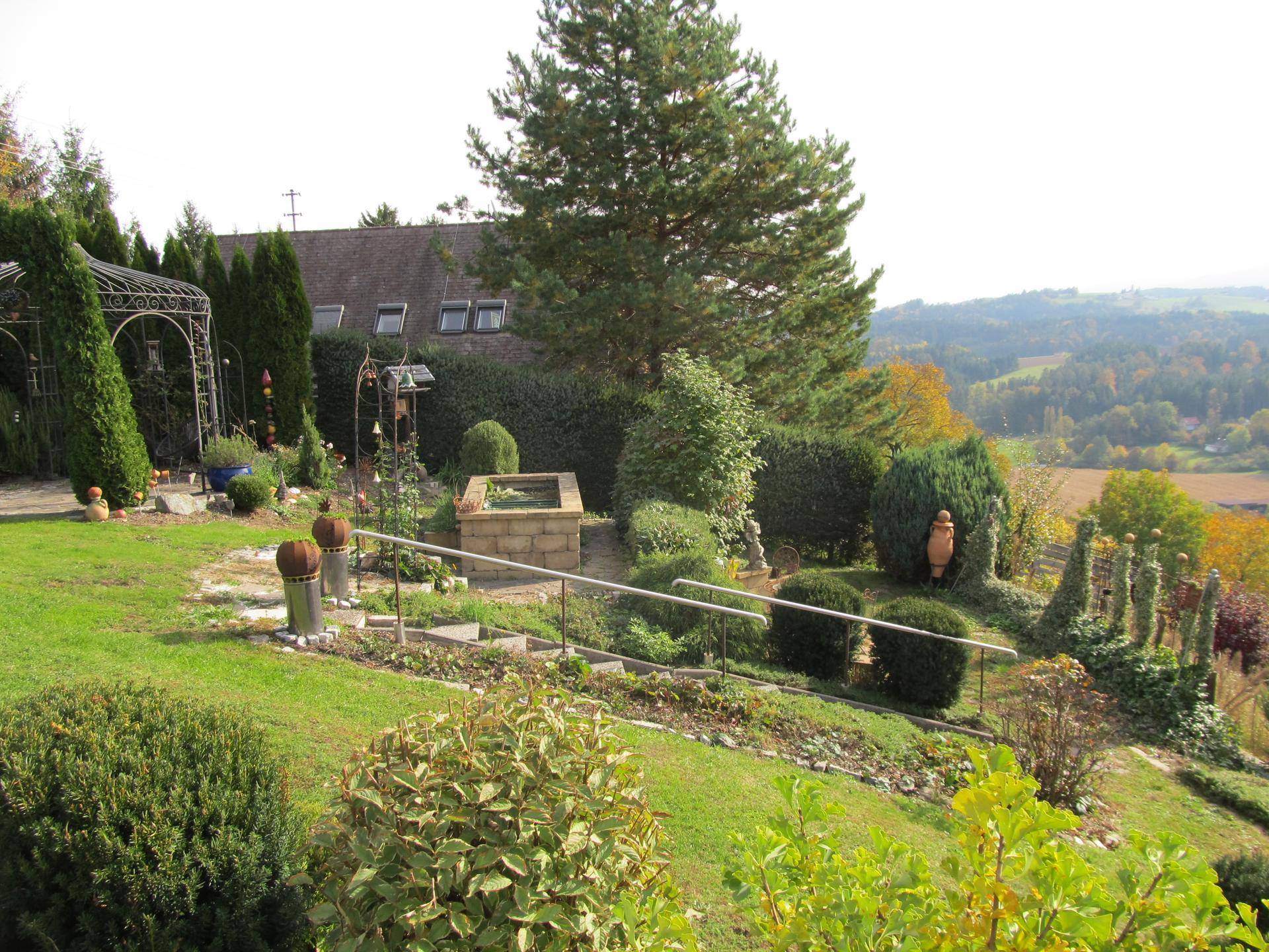 Weitläufiger Garten mit Treppen, Hecken und Blick auf das Haupthaus und die Landschaft.