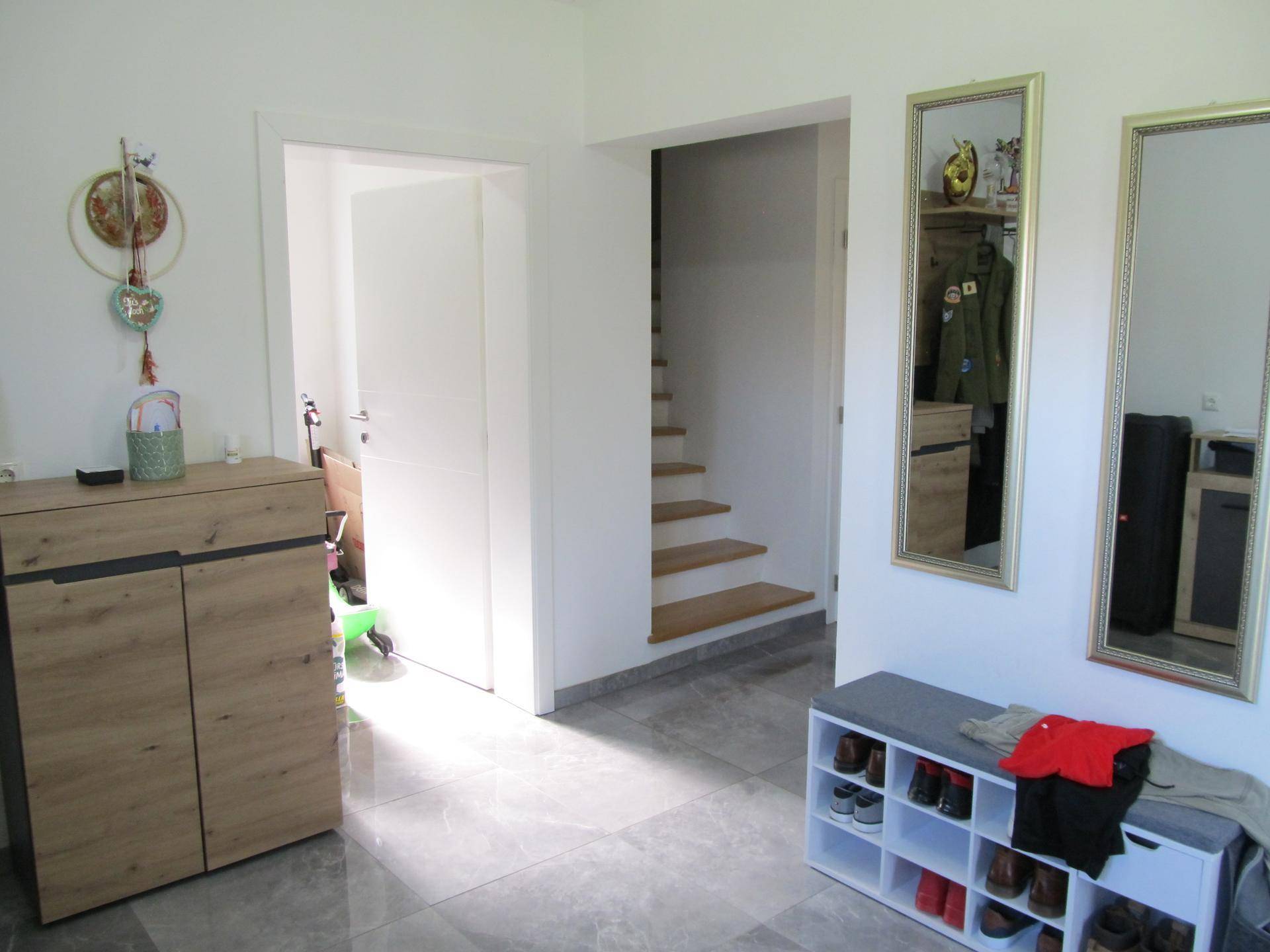 Heller Eingangsbereich mit modernen Fliesen, Garderobenschrank und Spiegeln.